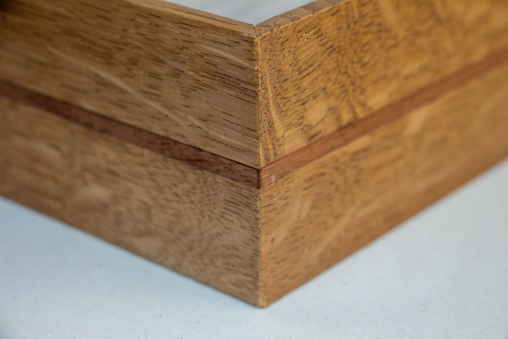 Veiled Alchemist 004 frame detail: corner close-up of the mitred joint, emphasizing the precise joinery, the warm grain of the Japanese elm, and the slim red-toned inlay line.