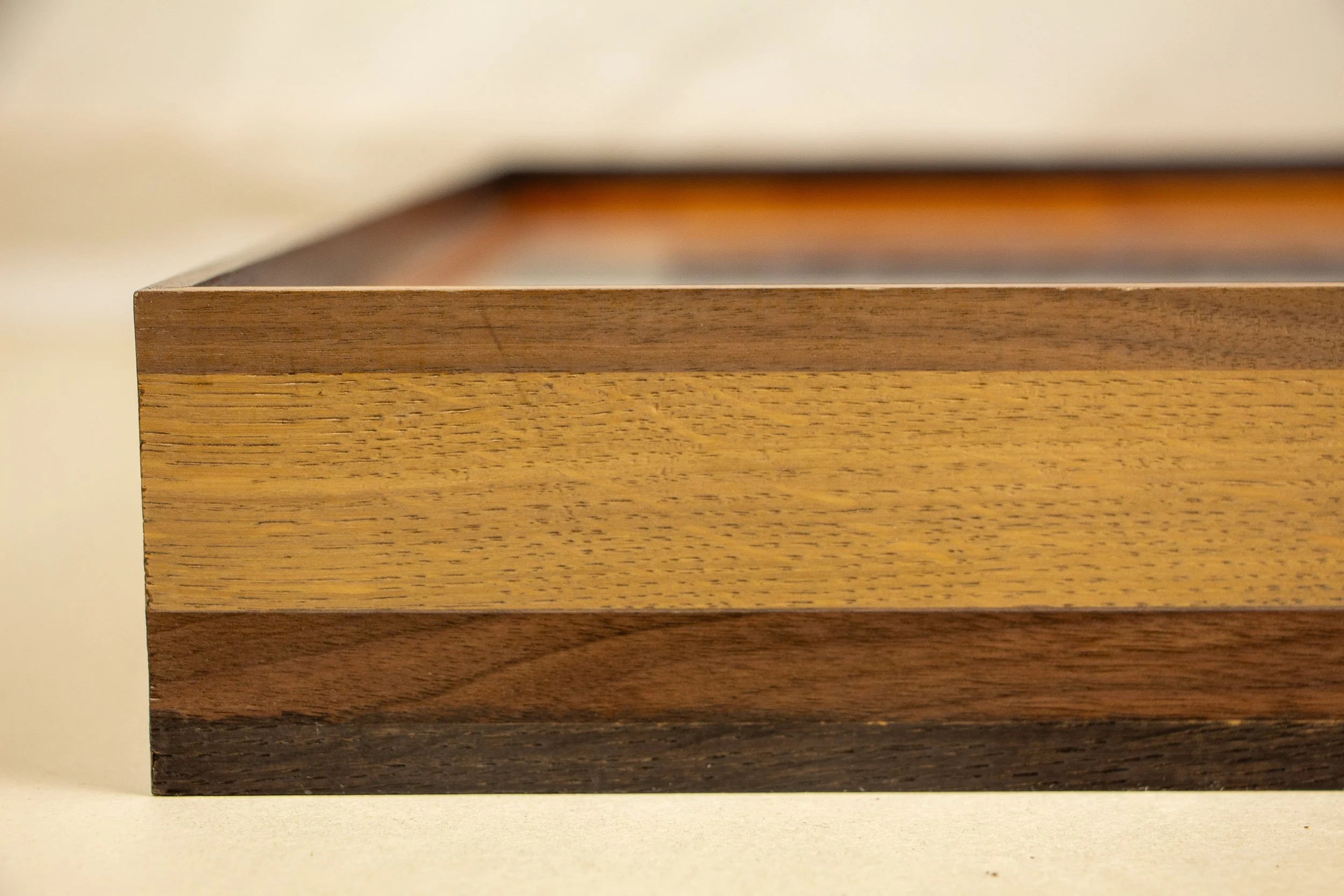 Mêlée of Discovery 005 frame detail: straight-on view of the frame side, emphasizing the horizontal layering of woods and subtle shifts in grain and tone.