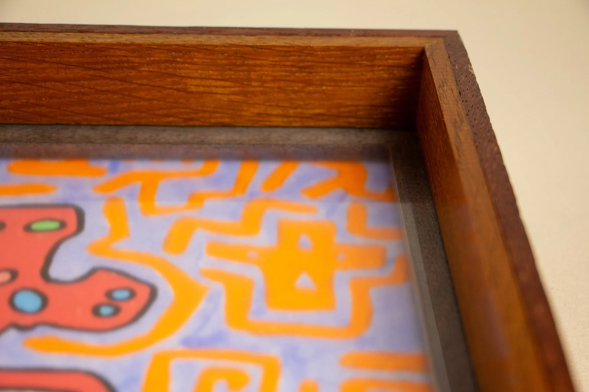 Unseen Signifiers 010 frame detail: angled close-up of the upper right frame corner, focusing on the depth of the wooden construction, the dark inner liner, and the orange symbols visible beneath the acrylic. mahogany, oak and beech wood.