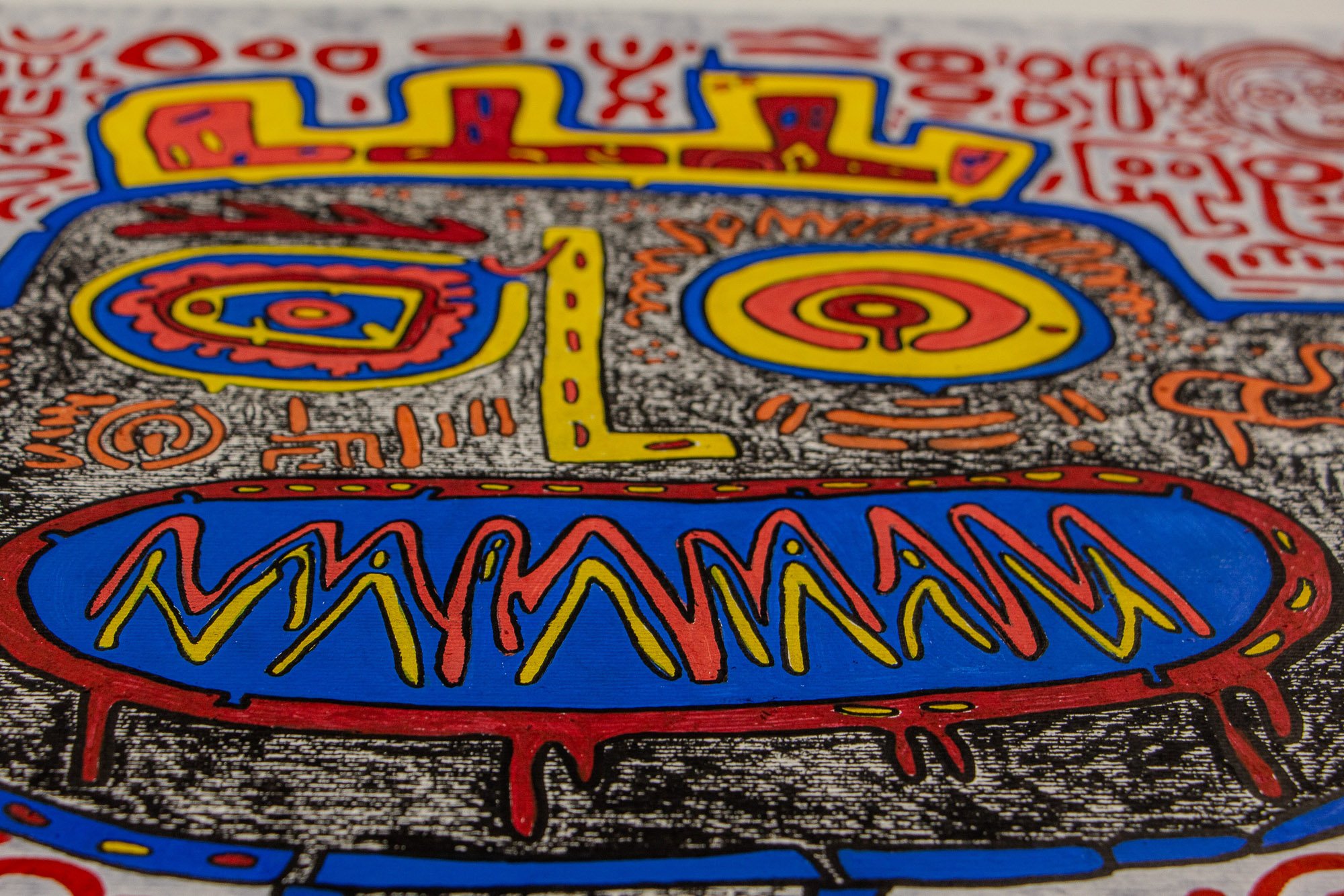 Unseen Signifiers 003 detail: close-up of a face with a stippled black-and-white ground, yellow and red crown-like form, circular eyes, and a vivid blue mouth shape edged in red.