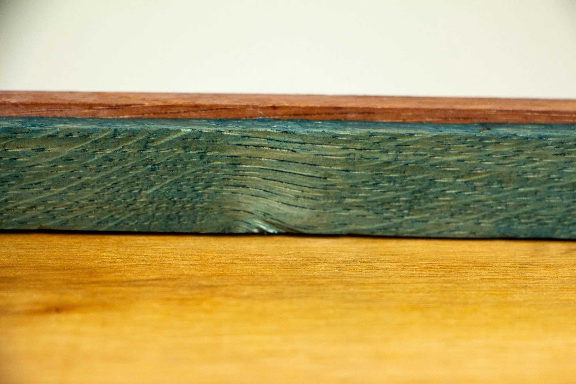 Unseen Signifiers 005 frame detail: reverse horizontal close-up of the frame, showing the olive-green inner support rim with visible wood grain, the thin reddish-brown outer edge above it, and the warm plywood back panel below. mahogany, oak and beec