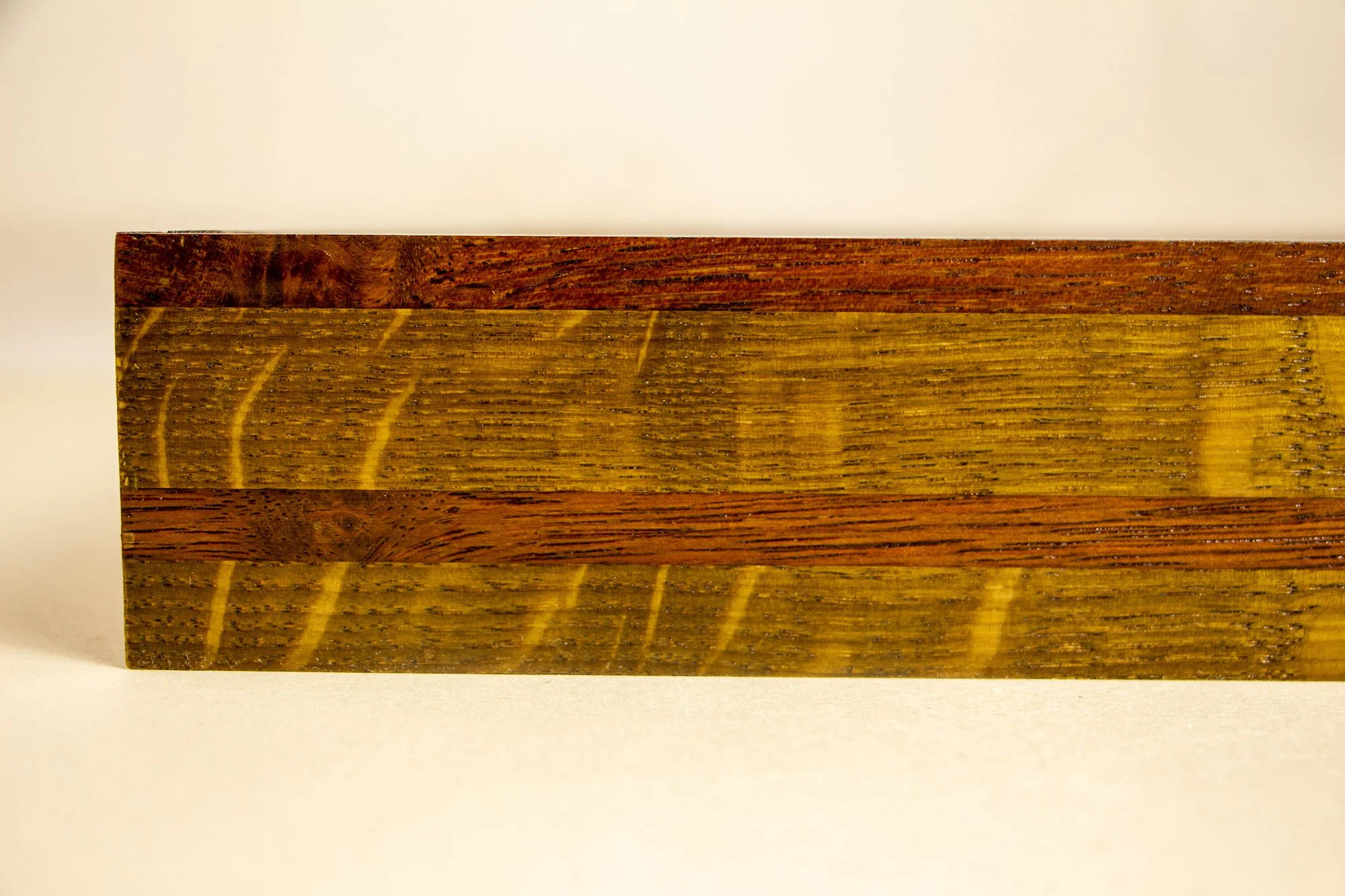 Unseen Signifiers 007 frame detail: straight-on close-up of the frame profile showing layered wood bands in warm golden-brown and reddish-brown tones. mahogany, oak and beech wood.