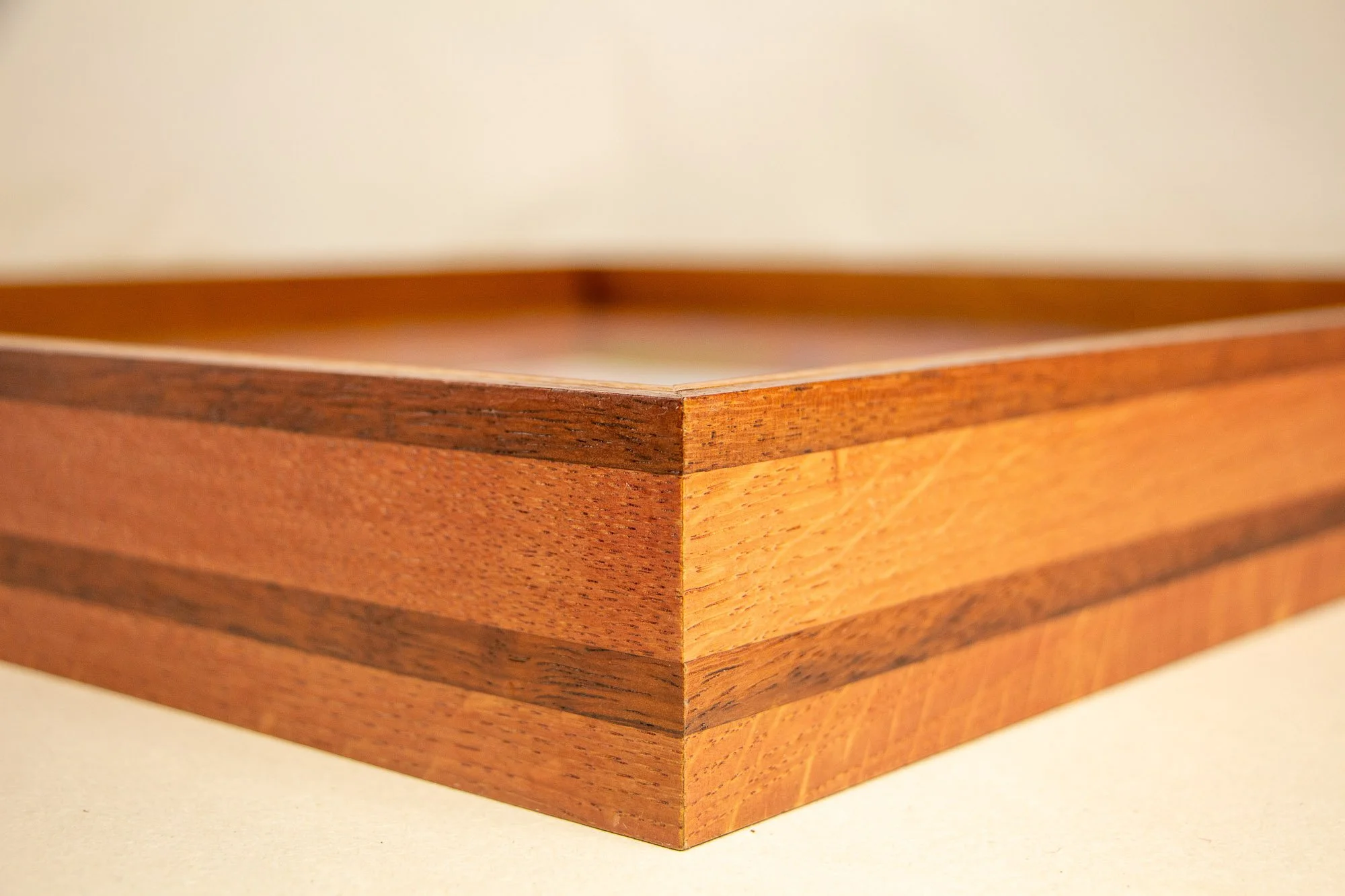 Unseen Signifiers 010 frame detail: corner perspective of the layered wooden frame, highlighting the mitered join, the acrylic top edge, and the contrast between the lighter and darker wood bands. mahogany, oak and beech wood.