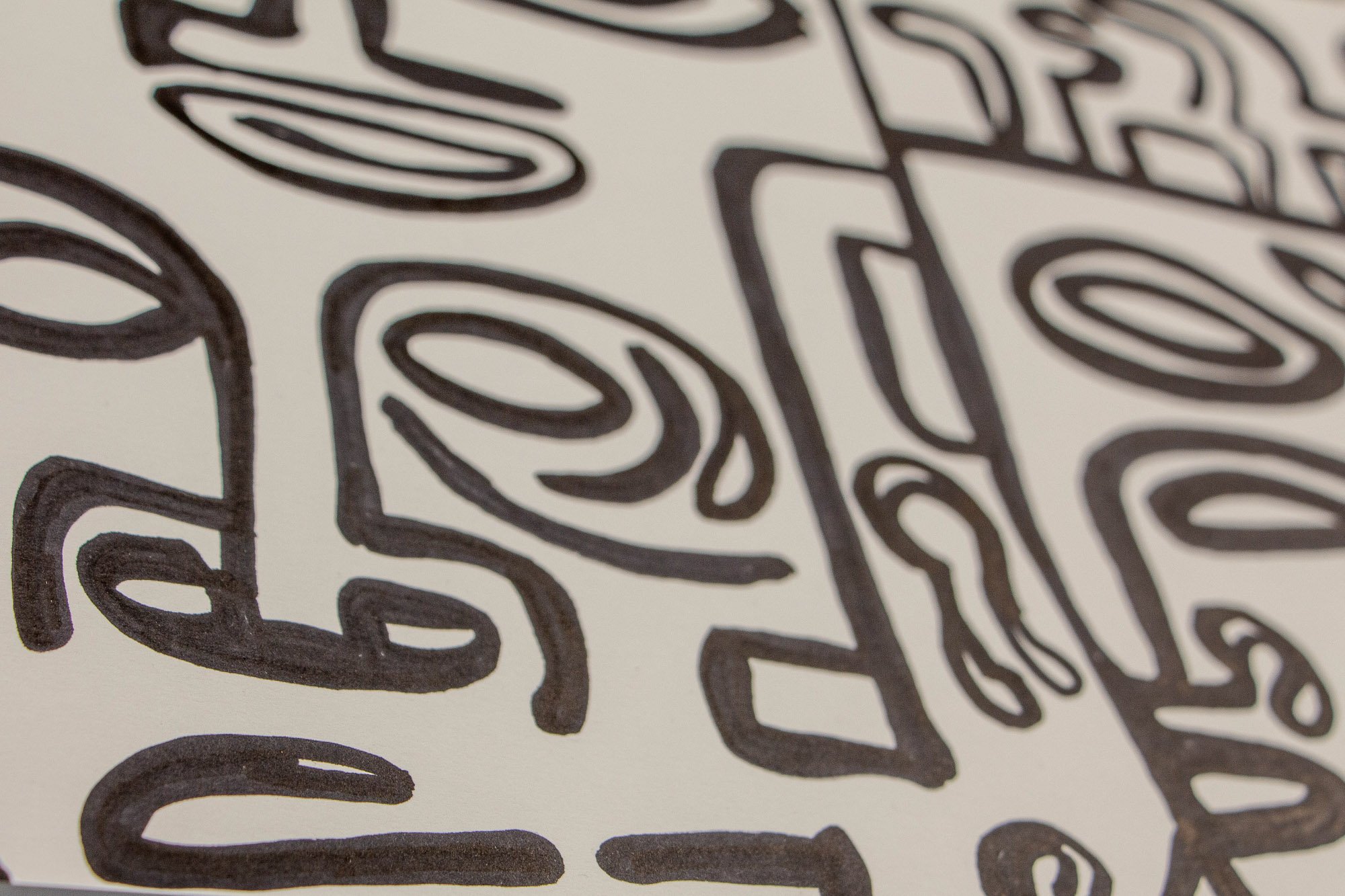 Veiled Alchemist 002 detail: close-up of an expressive face with heavy brow, wide eyes, and vertical teeth-like marks, emphasizing the bold graphic character and emotional charge of the black linework.