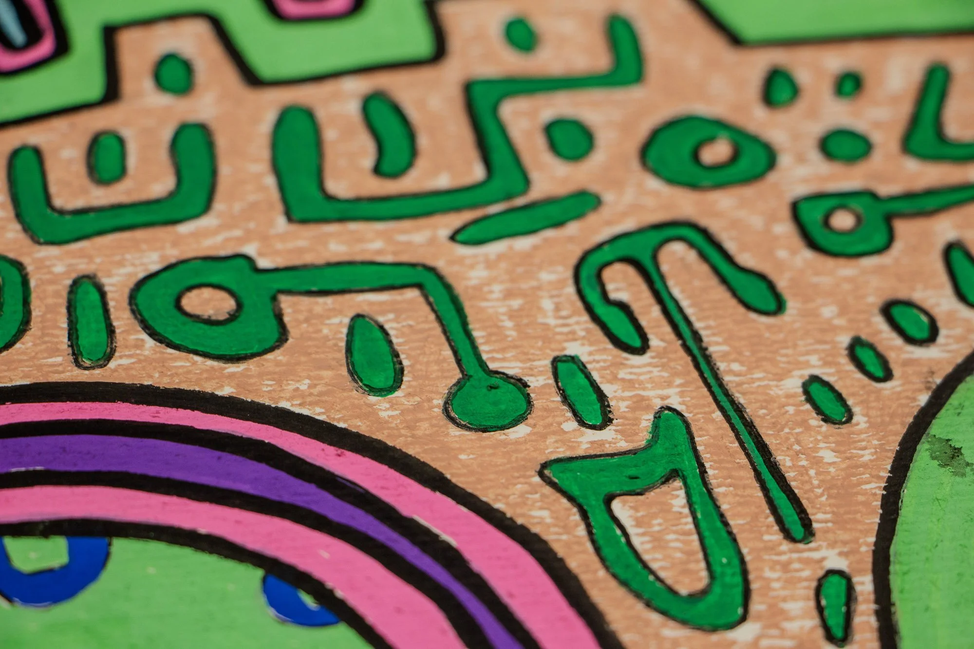 Unseen Signifiers 008 detail: close-up of green linear symbols on the warm beige ground, with black outlines and the curved pink-and-purple edge of the central face motif.