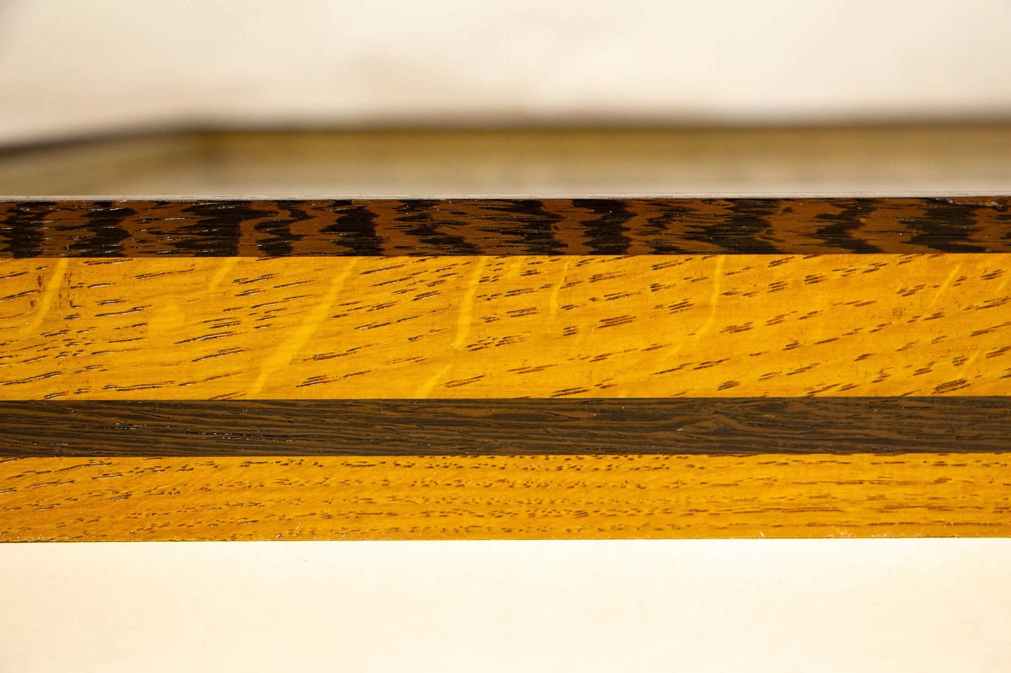 Elusive Cocoon 004 frame: frontal close-up of the frame profile, built from wengé and oak with a vivid yellow-toned band, darker horizontal strip, and visible natural grain variation.