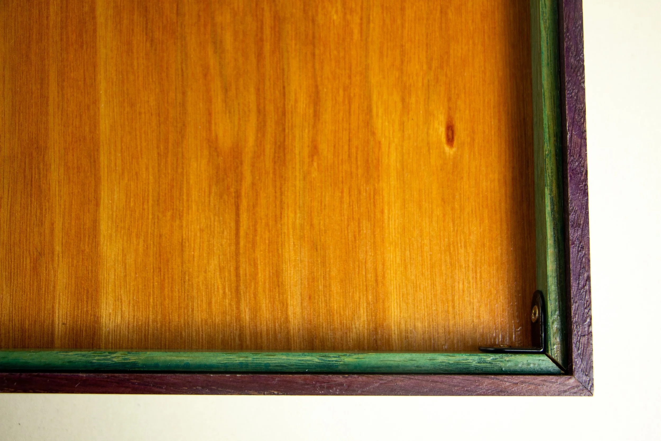 Formless Equation 001 frame: rear corner, green-stained spacer around warm amber back panel, neat L-bracket