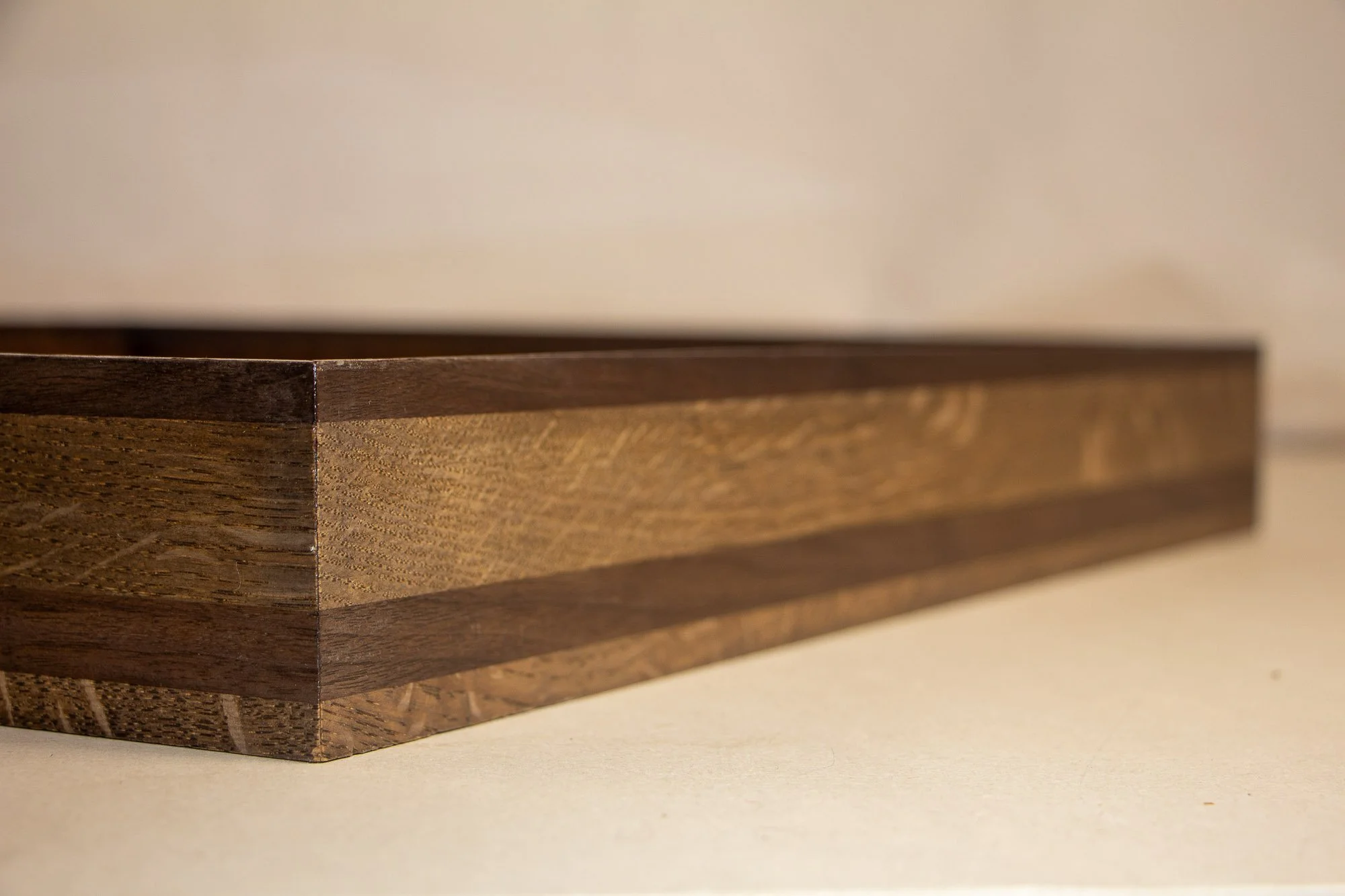 Luminous Parallax 001 frame: corner detail of the layered wooden frame, showing clean miter joinery and alternating dark and muted brown-grey bands that echo the series’ restrained tonal structure.