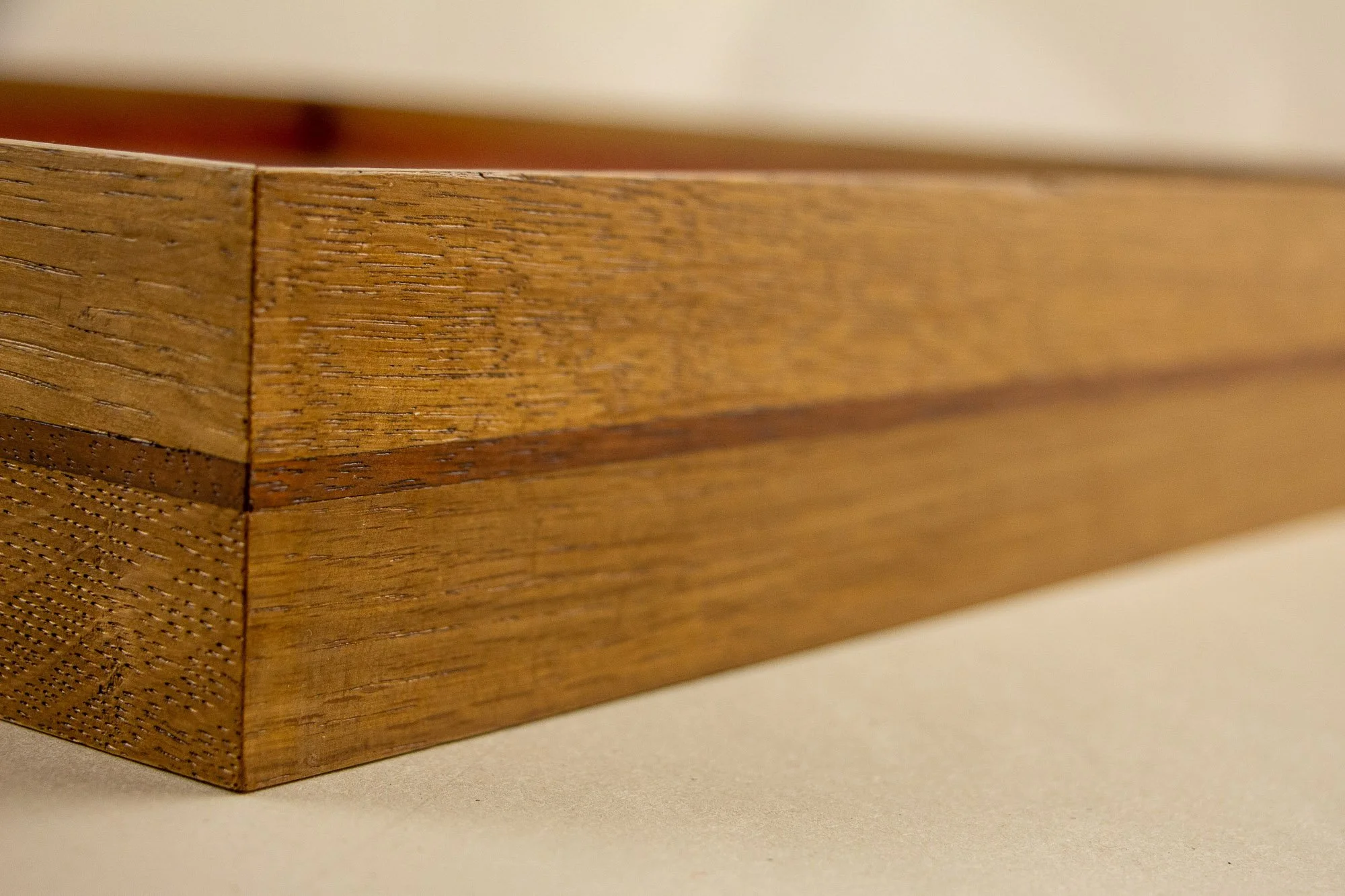 Veiled Alchemist 001 frame detail: angled side view of the handcrafted frame, showing the warm Japanese elm tone, the thin darker horizontal band, visible grain, and the calm depth of the layered profile.