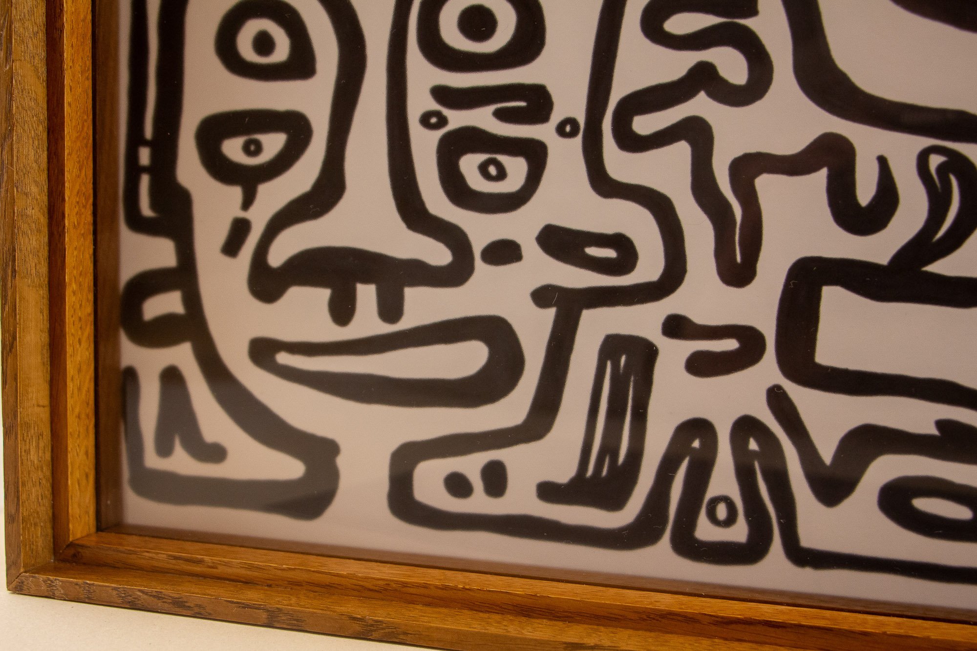 Close-up of a black and white abstract line drawing of a face, framed in wood.