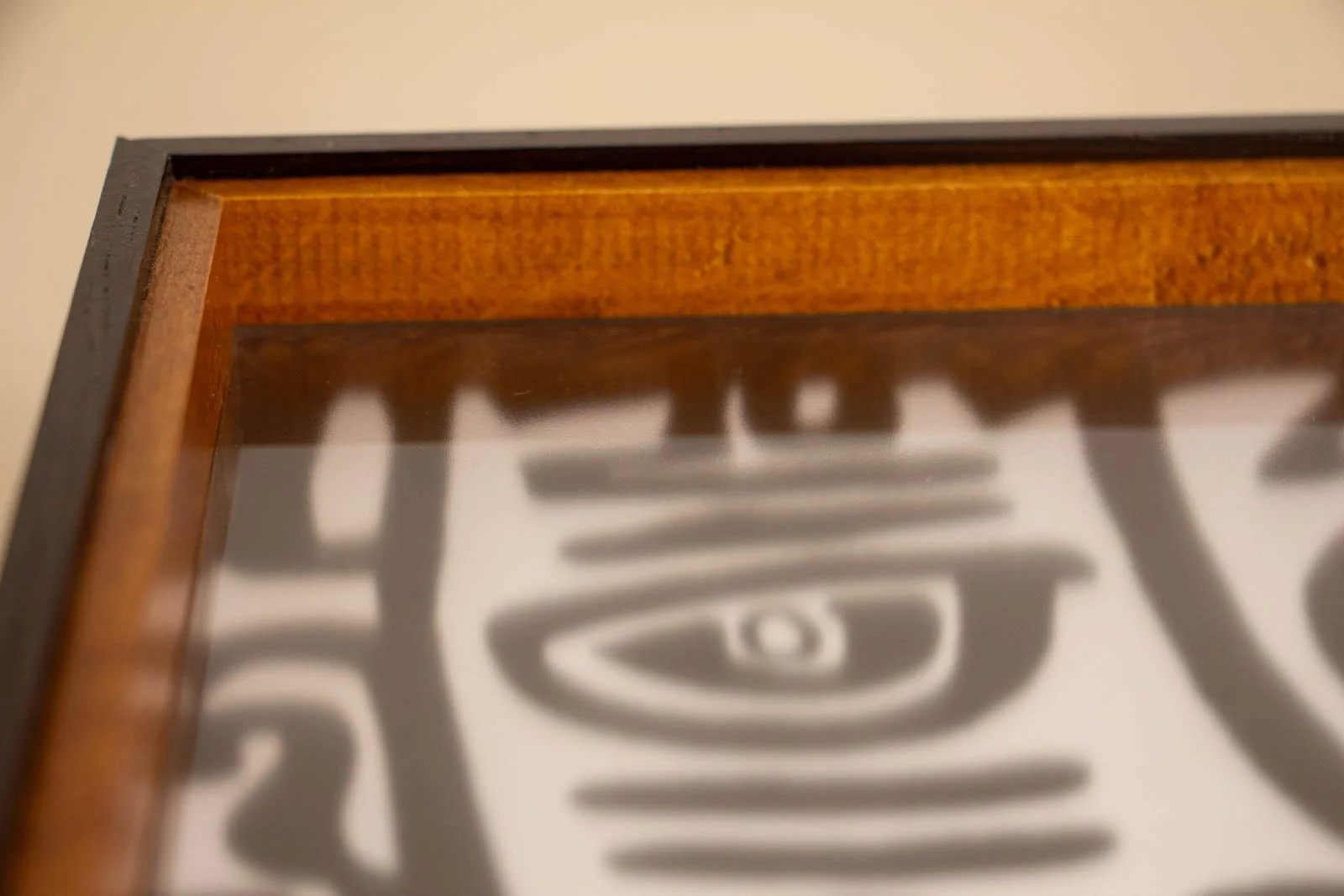 Formless Equation 004 frame: glass surface with soft reflection above eye motif, warm inner rim and wengé outer edge