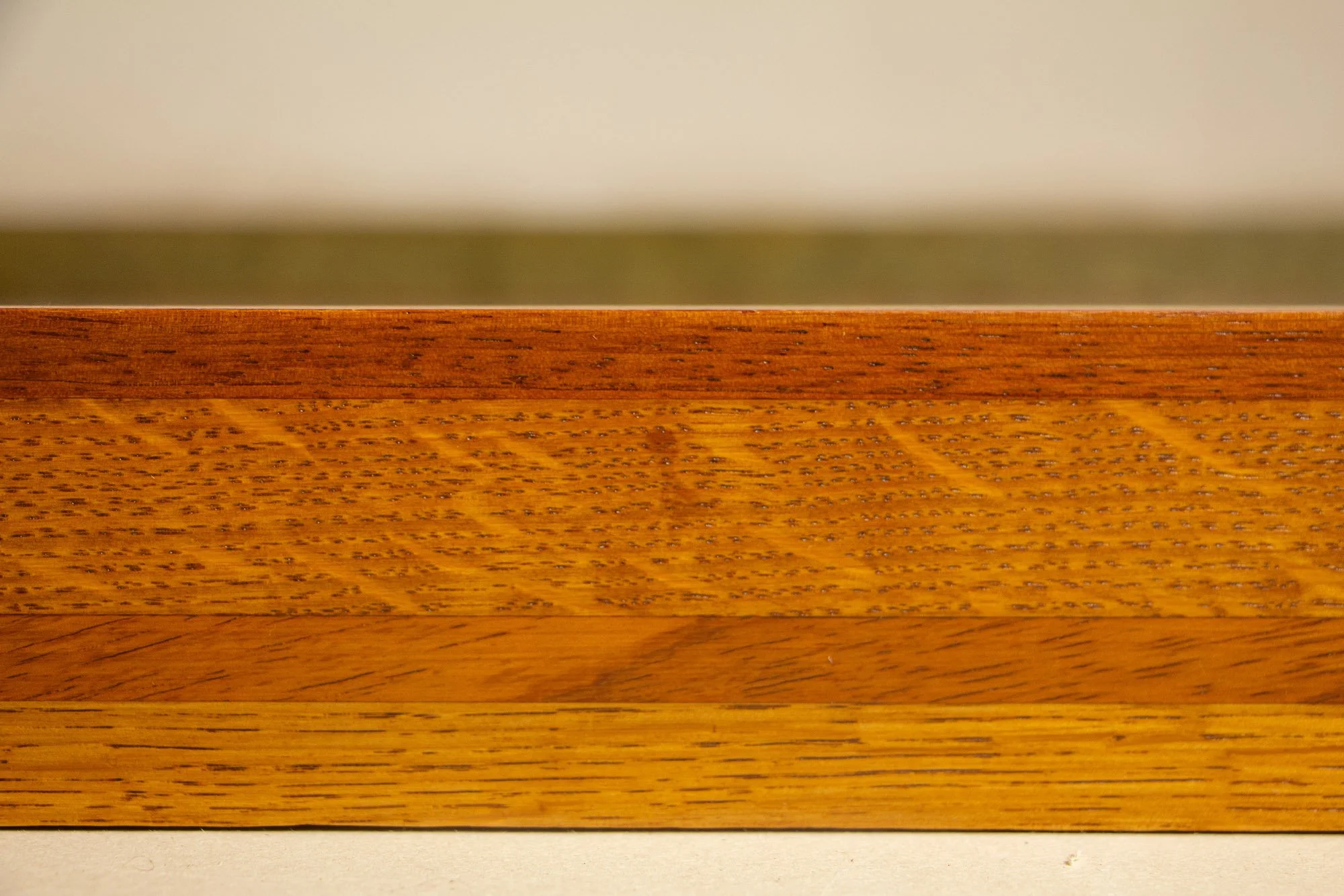 Unseen Signifiers 006 frame detail: frontal close-up of the upper frame edge, emphasizing the contrast between the smooth reddish-brown top strip and the textured golden wood below. mahogany, oak and beech wood.