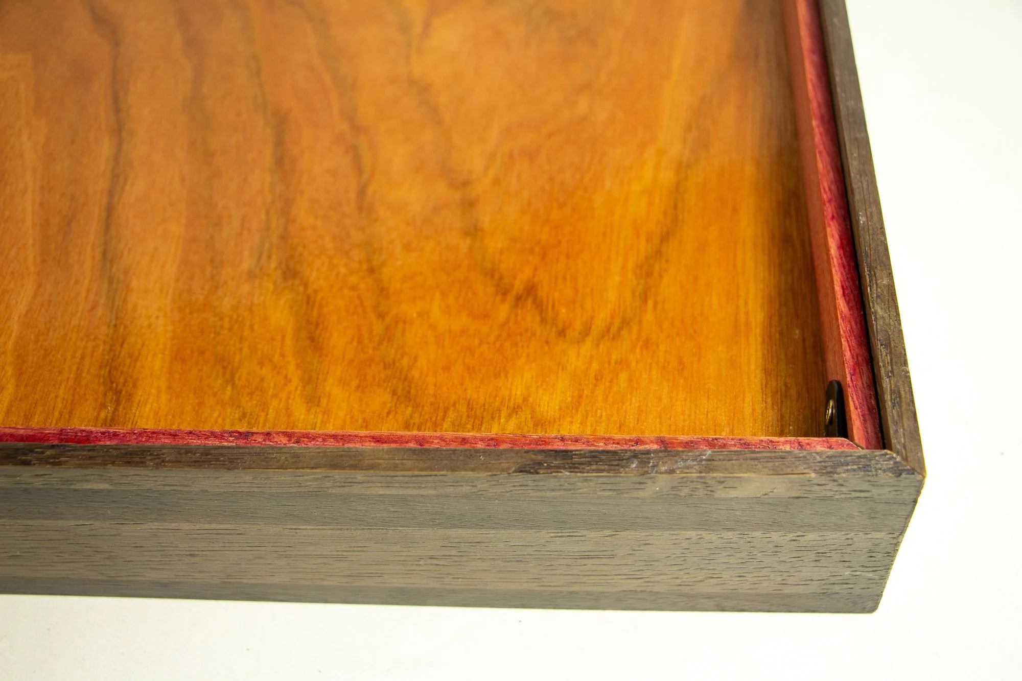 Luminous Parallax 002 frame: reverse corner detail showing the warm meranti plywood back, the red-toned inner backing rim, the dark outer frame, and the clean corner hardware.