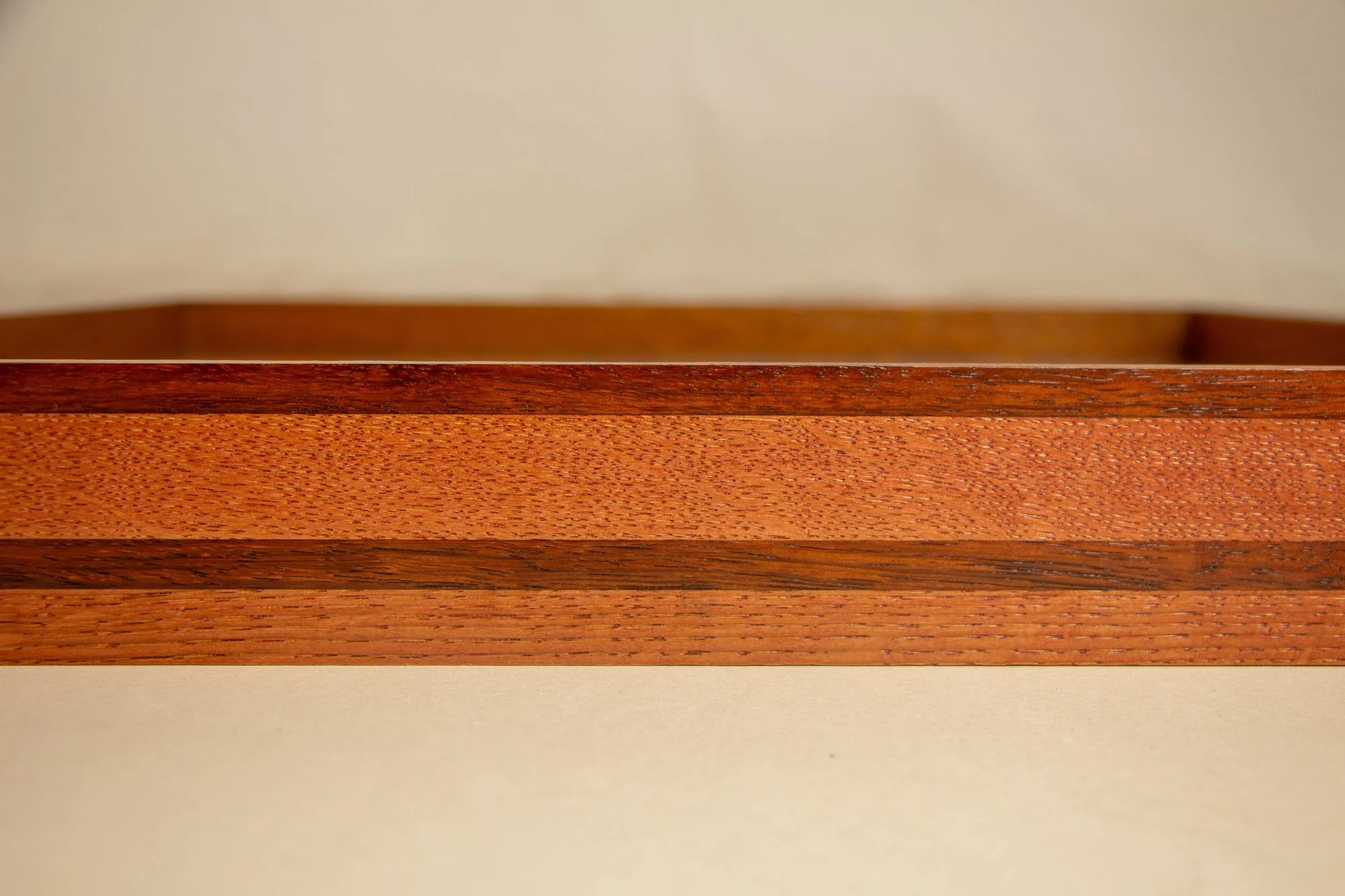 Unseen Signifiers 010 frame detail: frontal close-up of the frame profile, emphasizing the smooth lacquered finish, the warm reddish-brown top band, and the darker stripe set into the lighter wood body. mahogany, oak and beech wood.