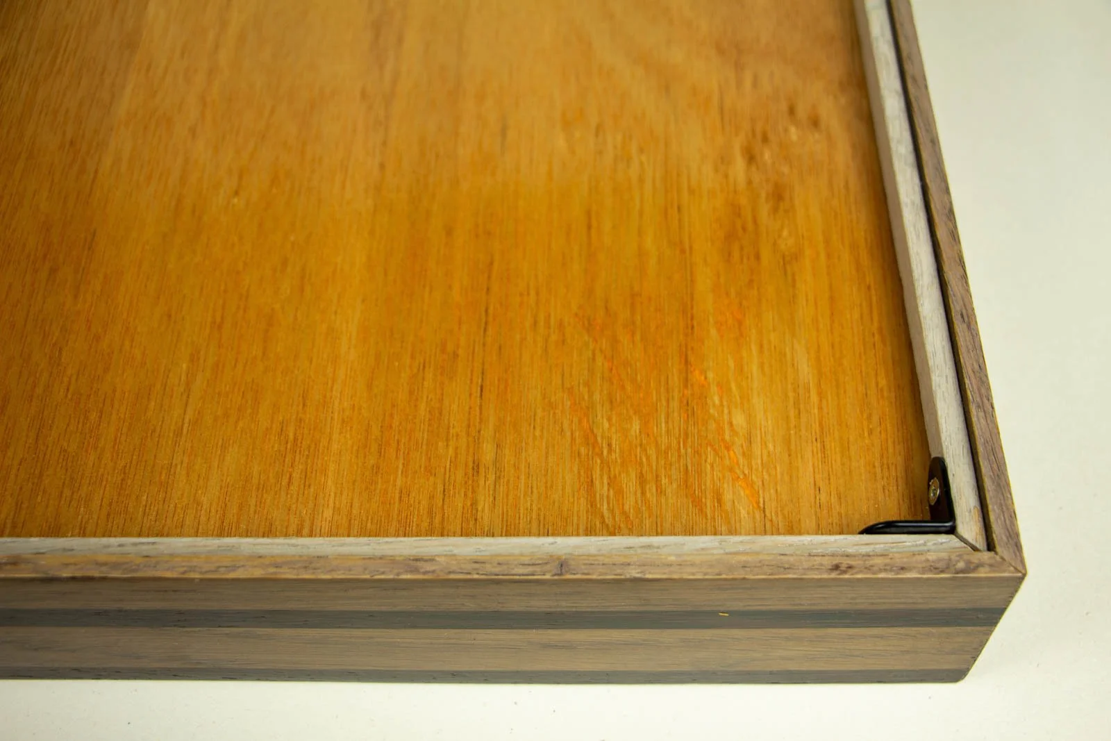 Synaptic Mythos 003 frame: rear, inner corner, honey-toned hardwood backboard; black L-bracket fixing panel to the frame