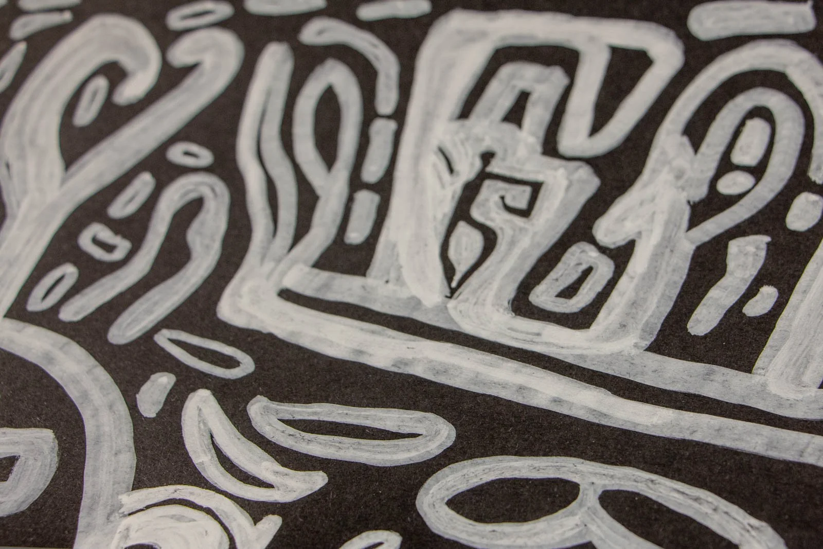 Metamorphic Entwining 001 detail: upper mask with heart emblem and ribbed bar above a wide eye and curved nose, layered white ink on black paper