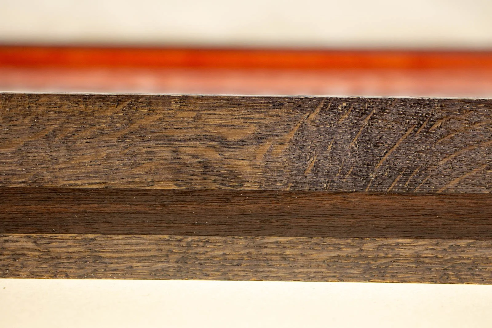 Flux Impromptu 002 frame: side segment, oak grain with subtle flecking; the walnut accent runs straight and even across the length