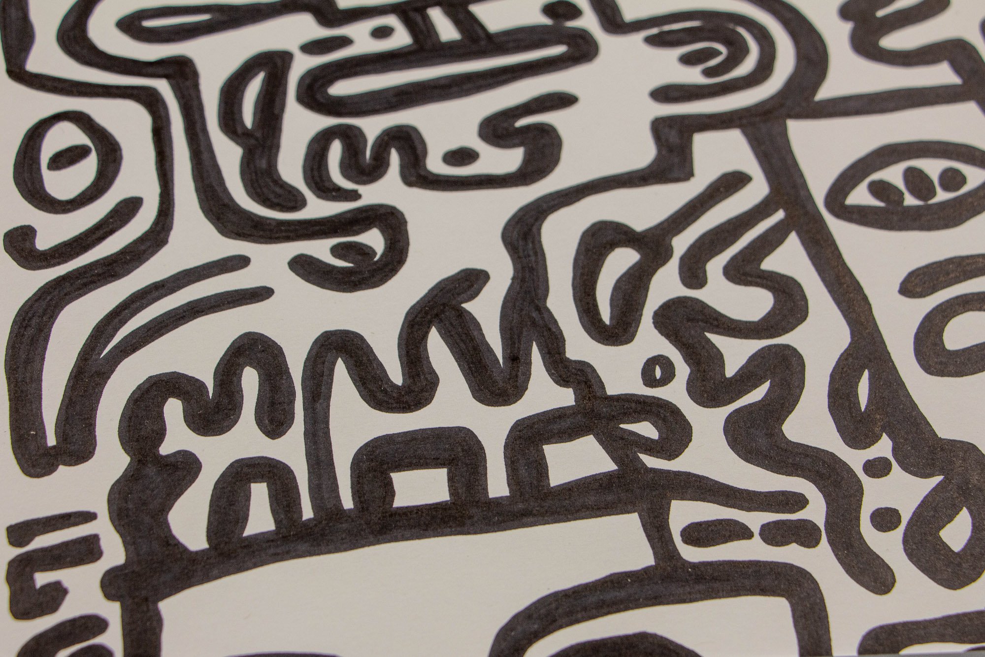 Veiled Alchemist 003 detail: angled close-up of the lower section, showing thick black lines forming a clustered arrangement of faces, curved shapes, and tightly nested abstract motifs.