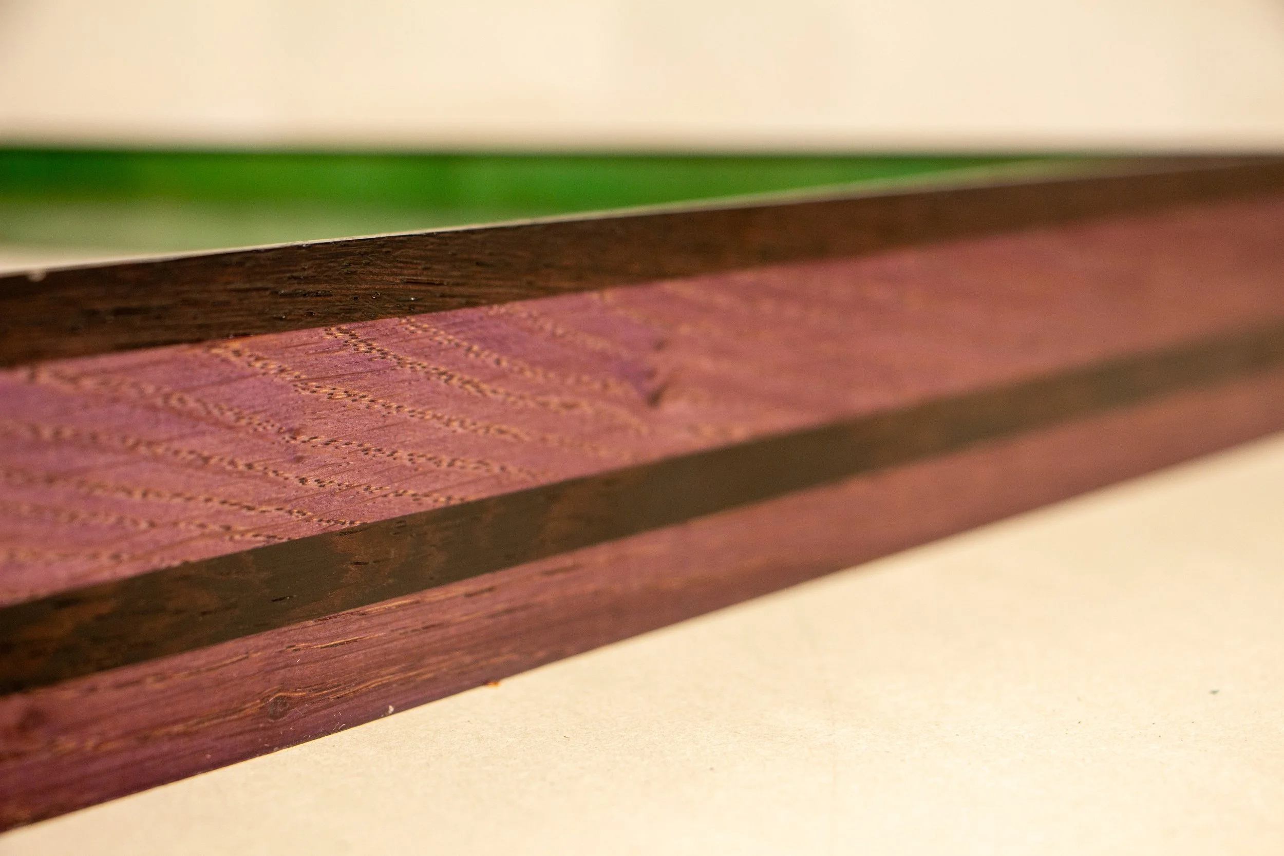 Formless Equation 001 frame: end view showing purpleheart body, central wengé stripe, and dark wengé top lip