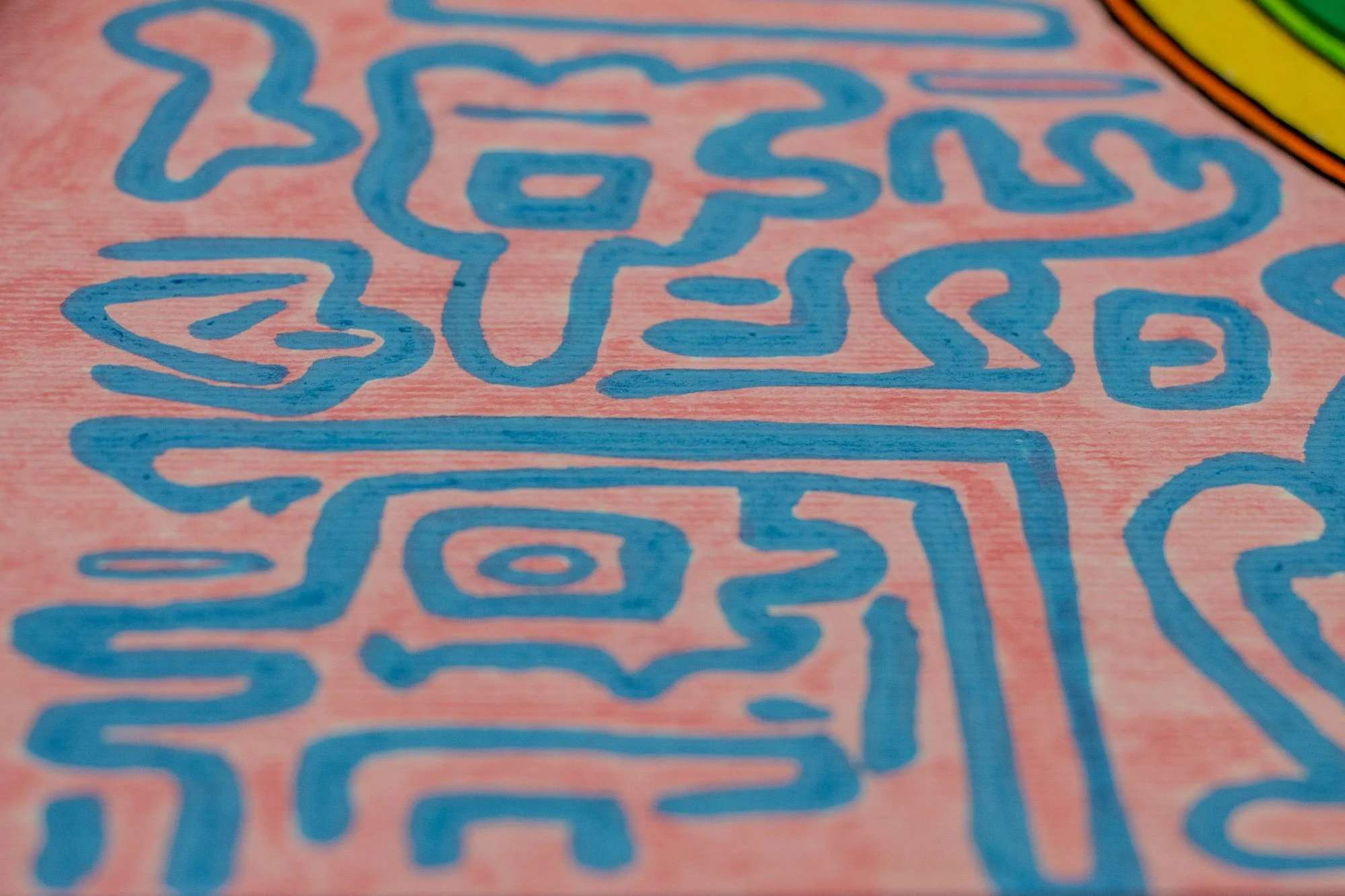 Unseen Signifiers 006 detail: close-up of the pink outer field with light-blue abstract signs, including a face-like glyph and rectangular symbolic forms.