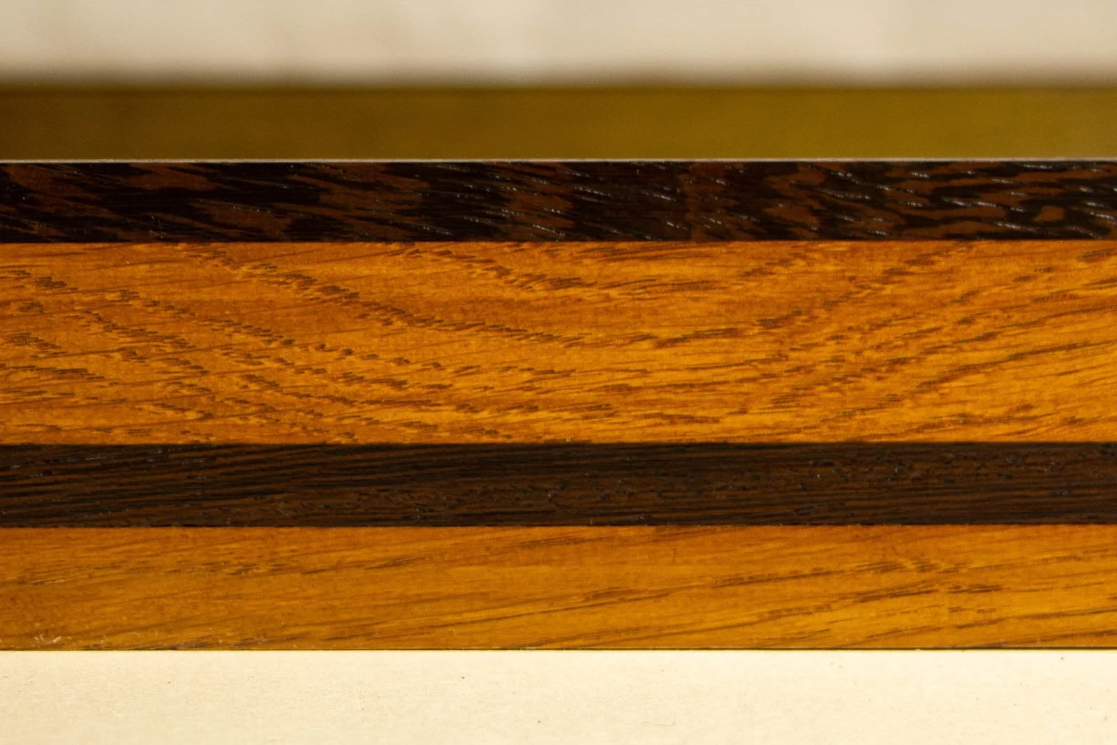 Metamorphic Entwining 003 frame: straight side view showing even oak figure, dark wengé top edge, and lower wengé stripe; smooth lacquer sheen