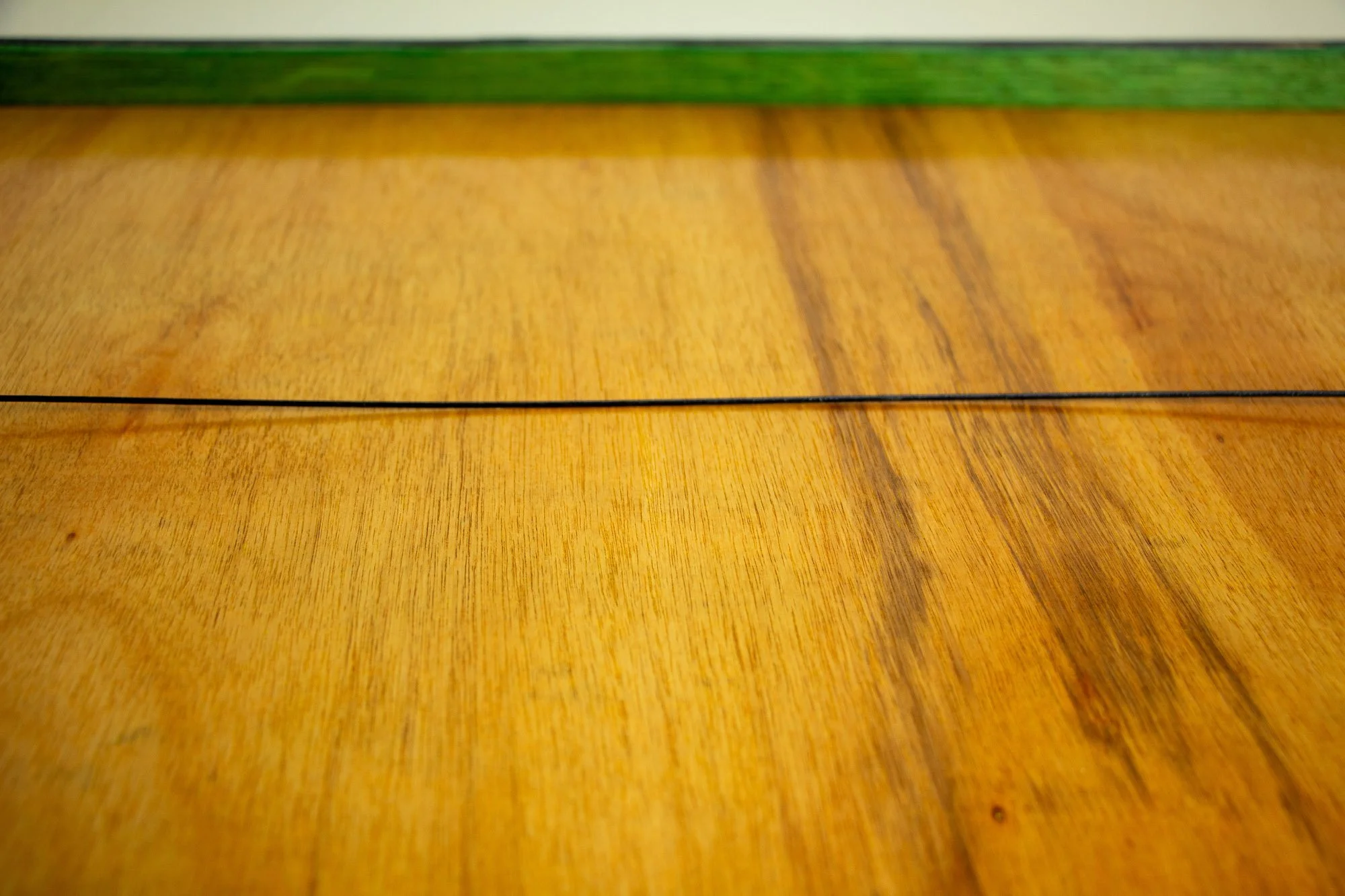 Unseen Signifiers 009 frame detail: rear view of the wooden back panel with the black hanging wire stretched across, and a green-toned inner frame strip visible along the top edge.