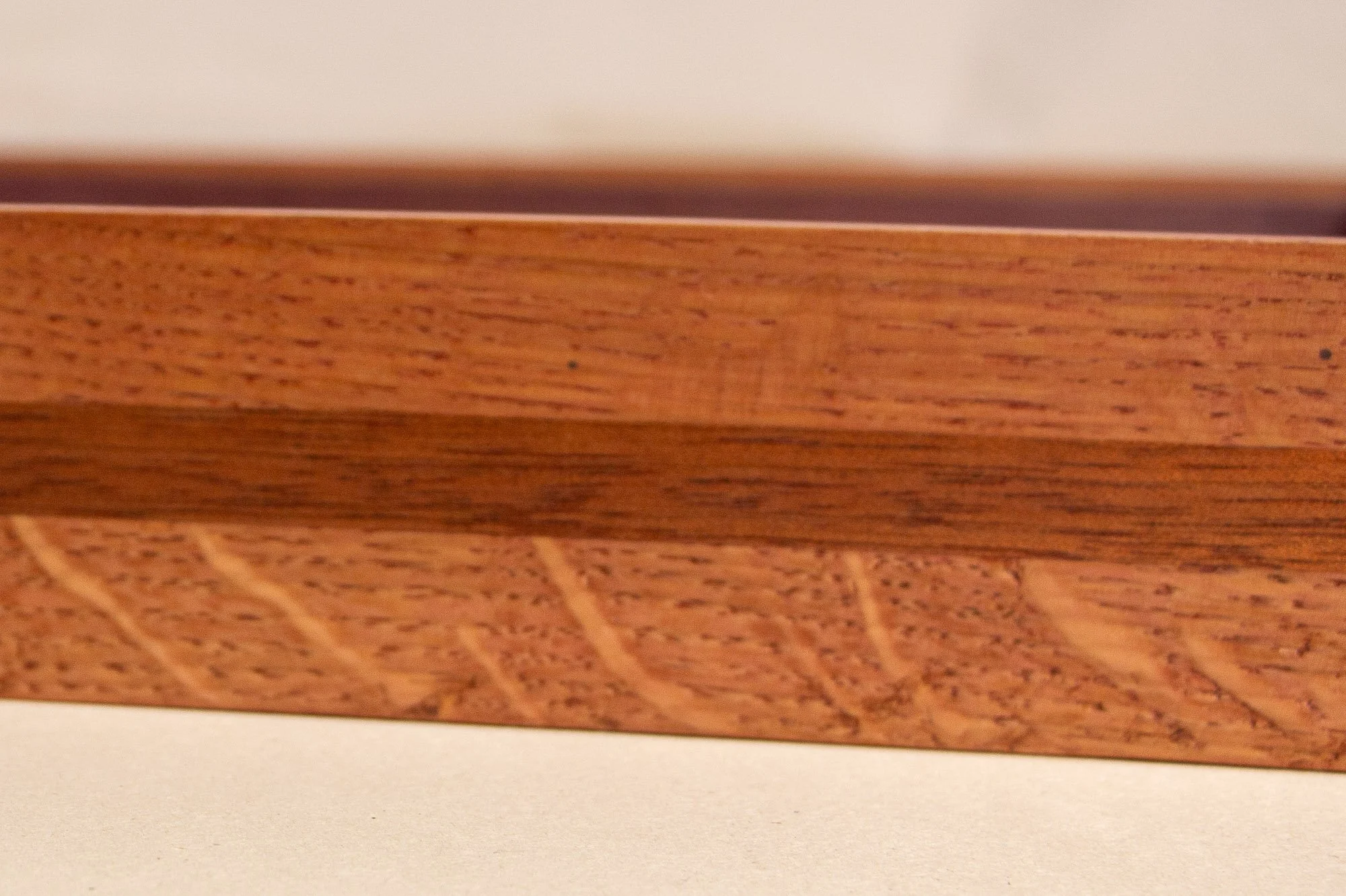 Eclipsing Gravitas 003 frame: frontal macro of the frame profile, showing the warm outer oak, the darker mahogany band, and the textured lower section of the layered construction in shallow focus.