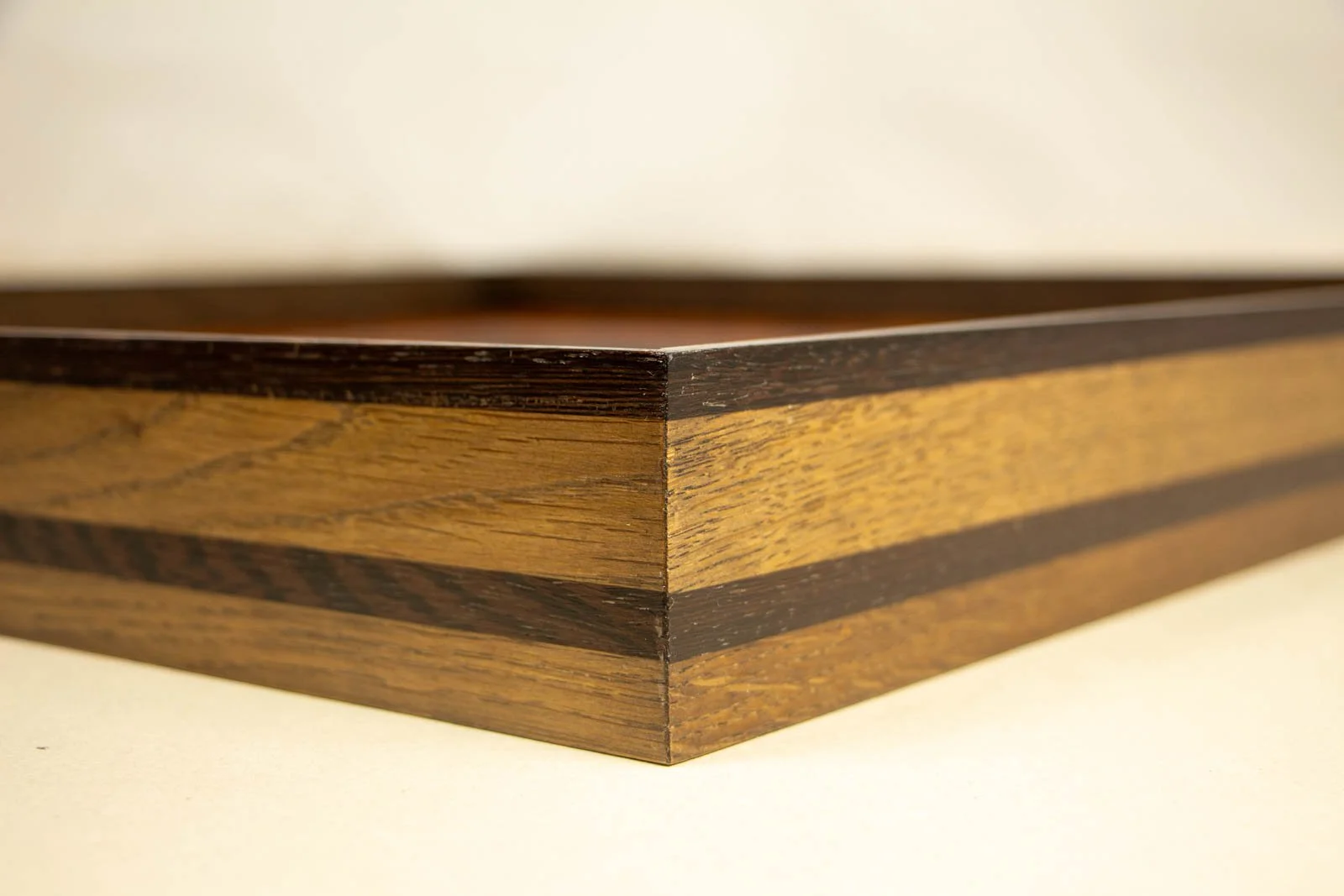 Synaptic Mythos 003 frame: outer corner in perspective, slim dark wengé cap over oak with a continuous mid-level wengé band; crisp 45° profile