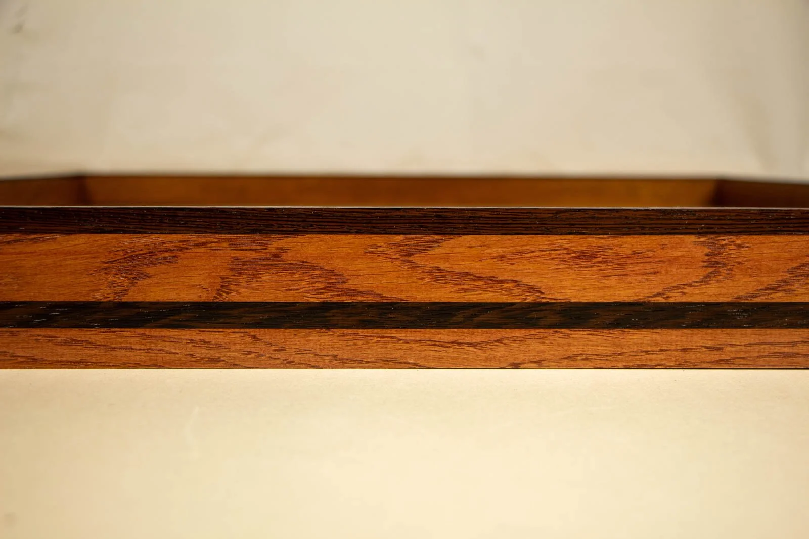 Metamorphic Entwining 001 frame: long run of cherry-toned oak grain with dark wengé top edge, open pores visible