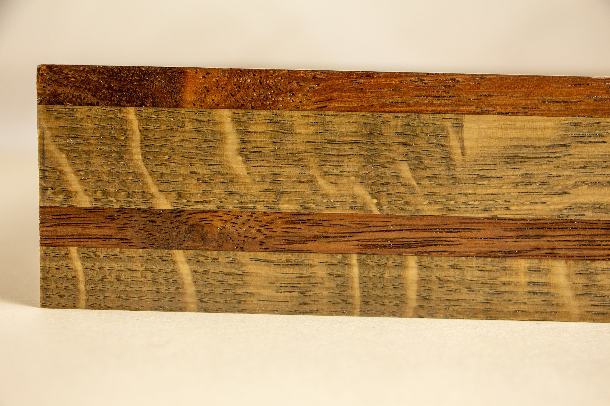 Unseen Signifiers 001 frame detail: straight-on close-up of the frame side, showing the contrast between the dark reddish top strip, the broad lighter oak section, and the darker horizontal band running through the middle. mahogany, oak and beech woo