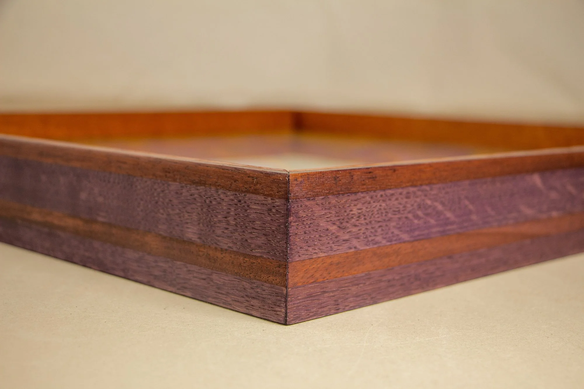 Unseen Signifiers 009 frame detail: angled corner view of the custom wooden frame, showing layered dark plum and warm brown wood tones beneath the clear acrylic front. mahogany, oak and beech wood.