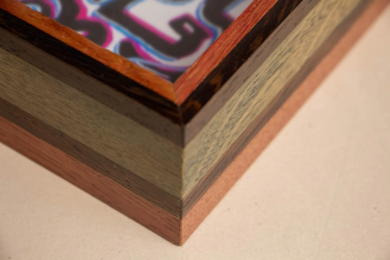 Silence’s Caesura Artwork 003 frame detail: outside mitre—two dark wenge bands, pink and blue stained oak field. clean 45° join.