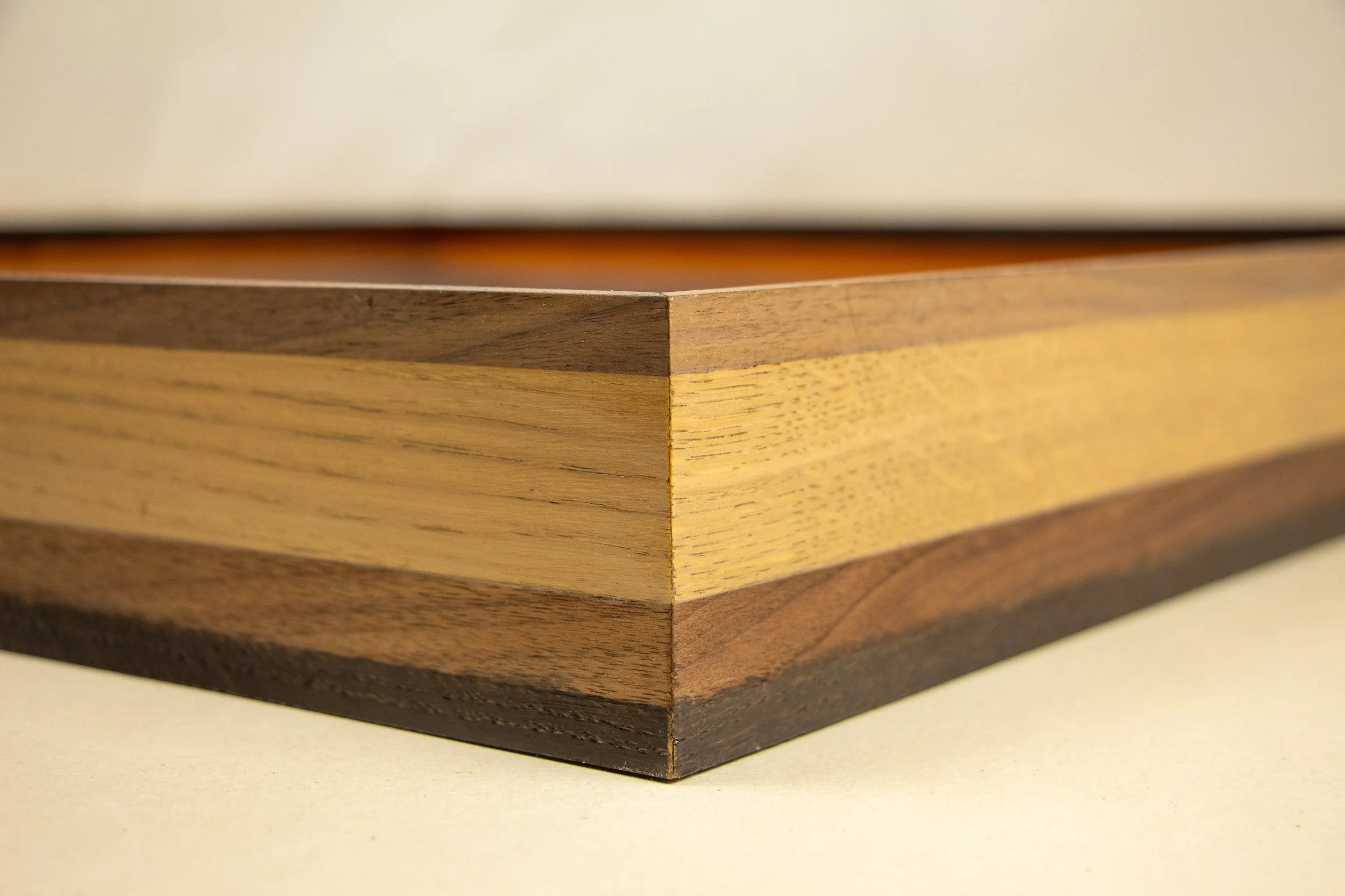 Mêlée of Discovery 005 frame detail: close-up of a sharp corner join showing the layered wooden frame in contrasting light and dark bands.