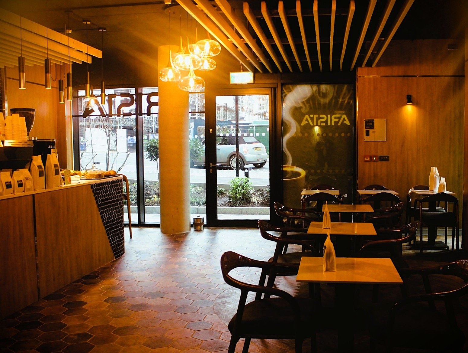 Arista - completed cafe interior fit-out in Brentford, London, with warm timber and bespoke seating.
