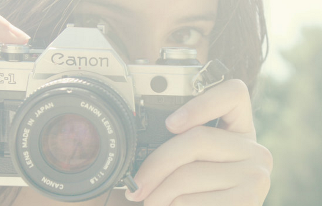 A person holding a vintage Canon film camera, with their eye visible in the background. Photo edited by Mary Perrino.