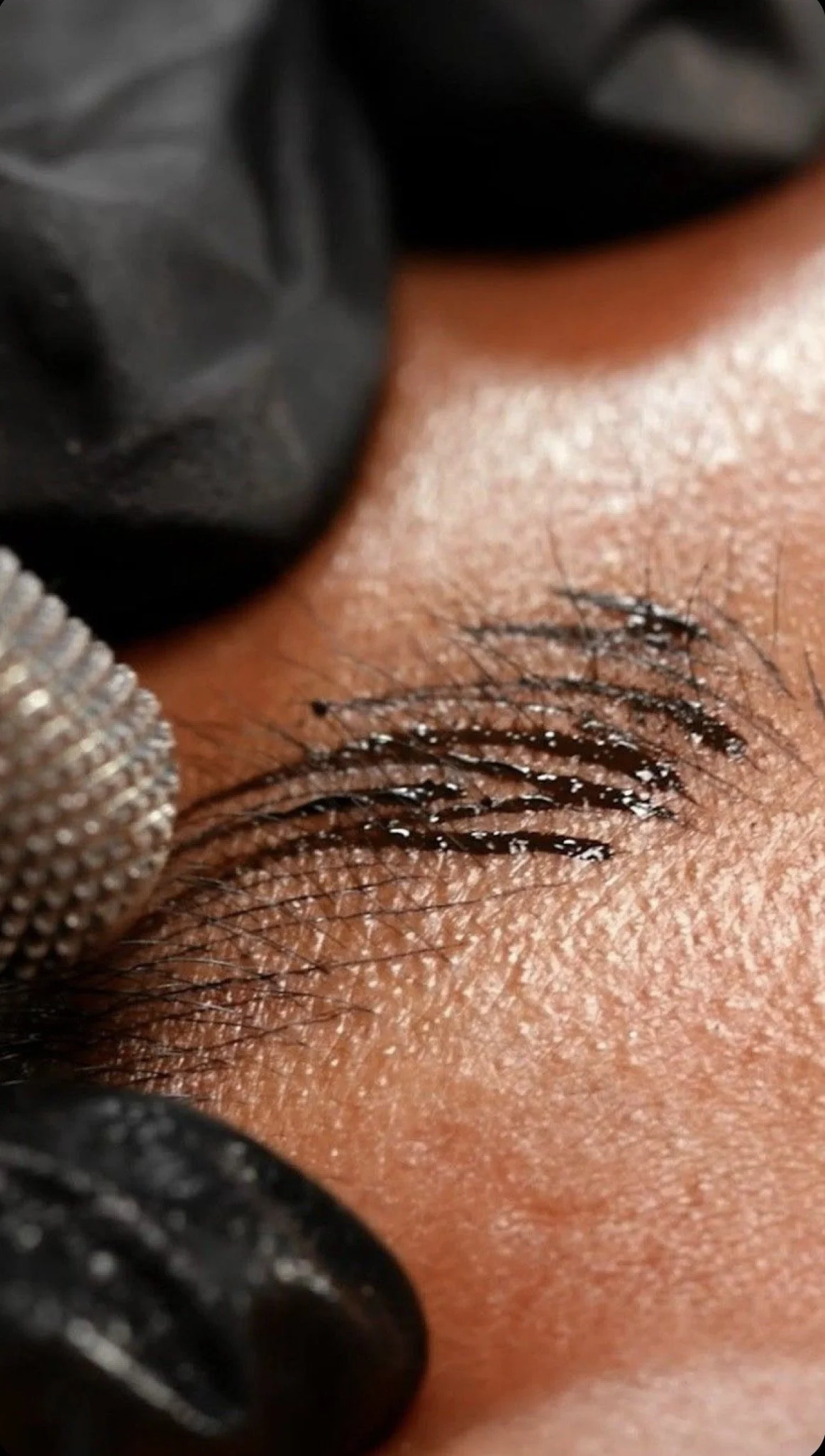Close-up of a person's eye with brown iris, dark eyelashes, and eyebrow, with sunlight illuminating the skin around the eye.