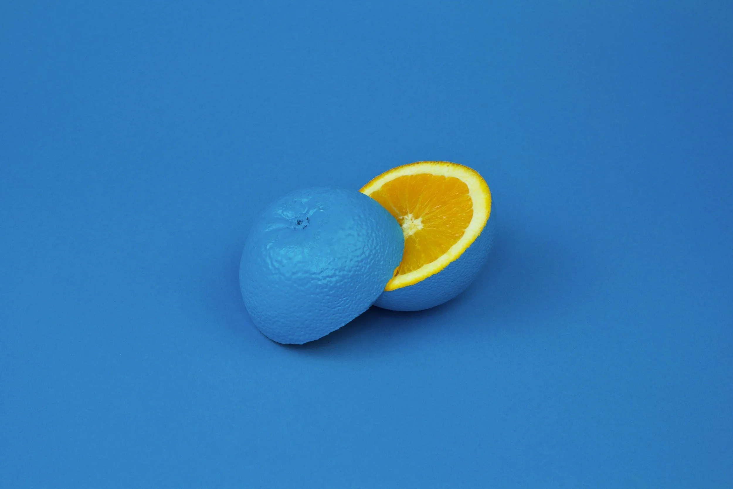 A blue-orange, where one half of the orange is peeled to show the inside, and the other half is unpeeled.