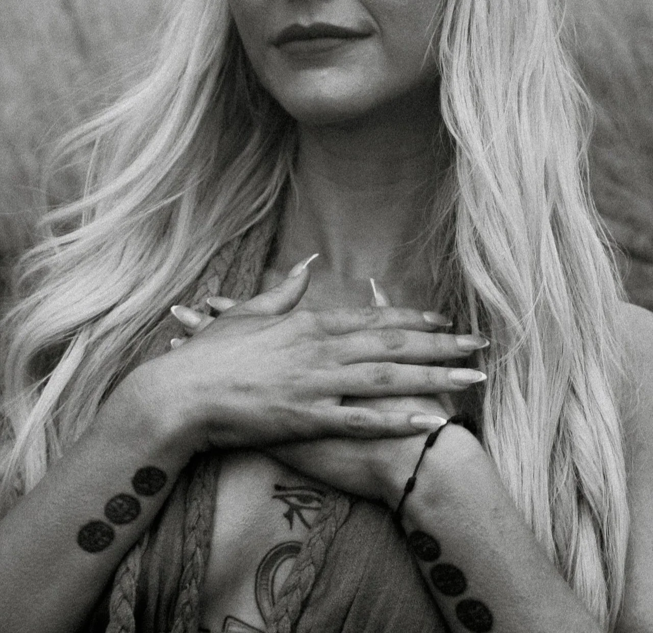 Close-up black-and-white image of a woman holding her hands over her heart