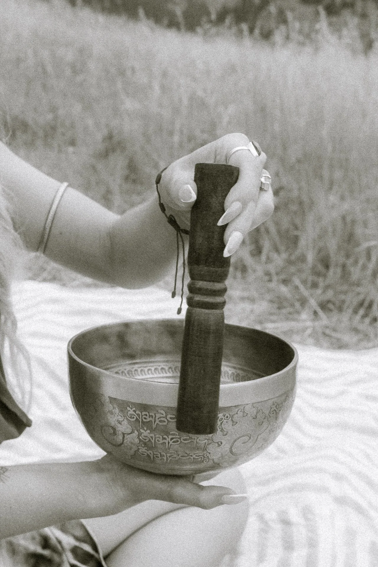 Hand striking a singing bowl during a grounding spiritual sound healing session