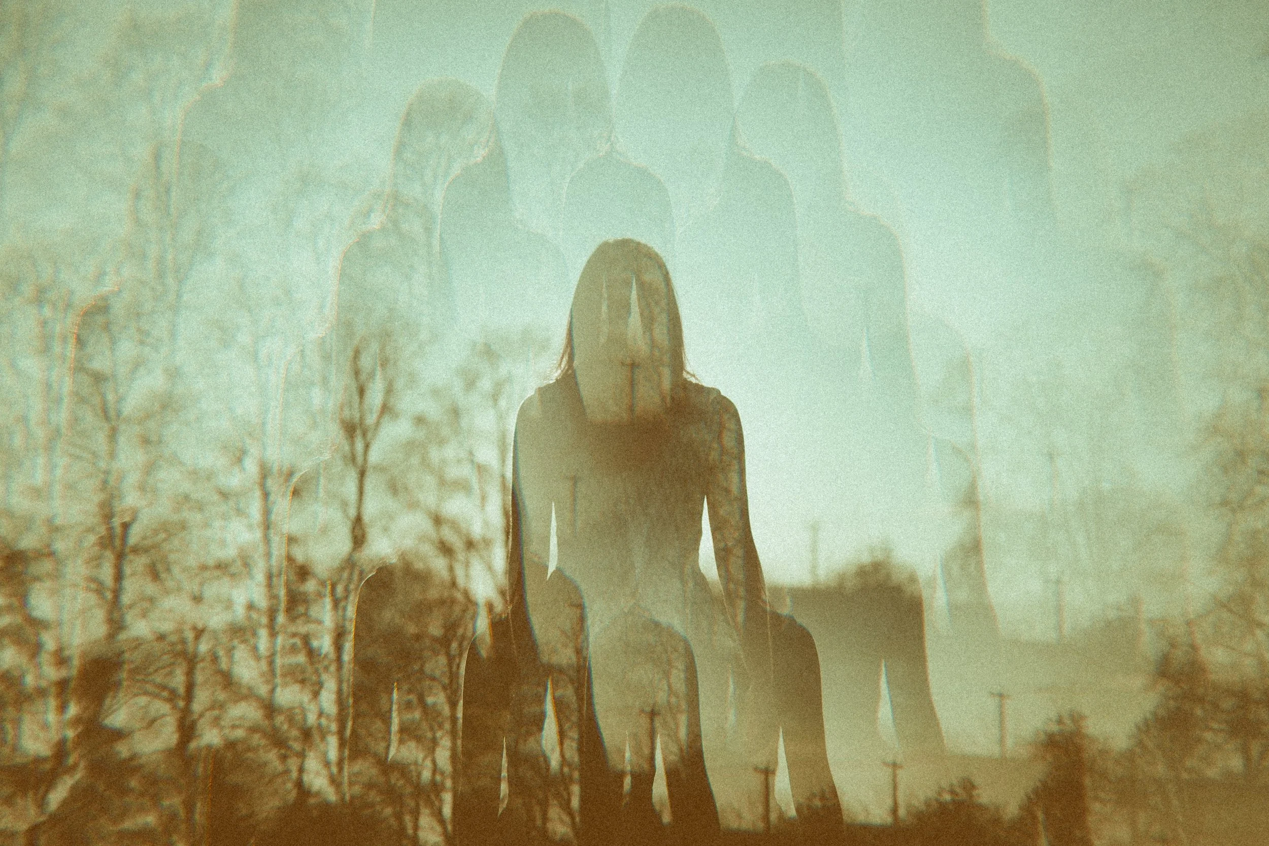 Double-exposure image of a seated figure with layered silhouettes against a landscape background