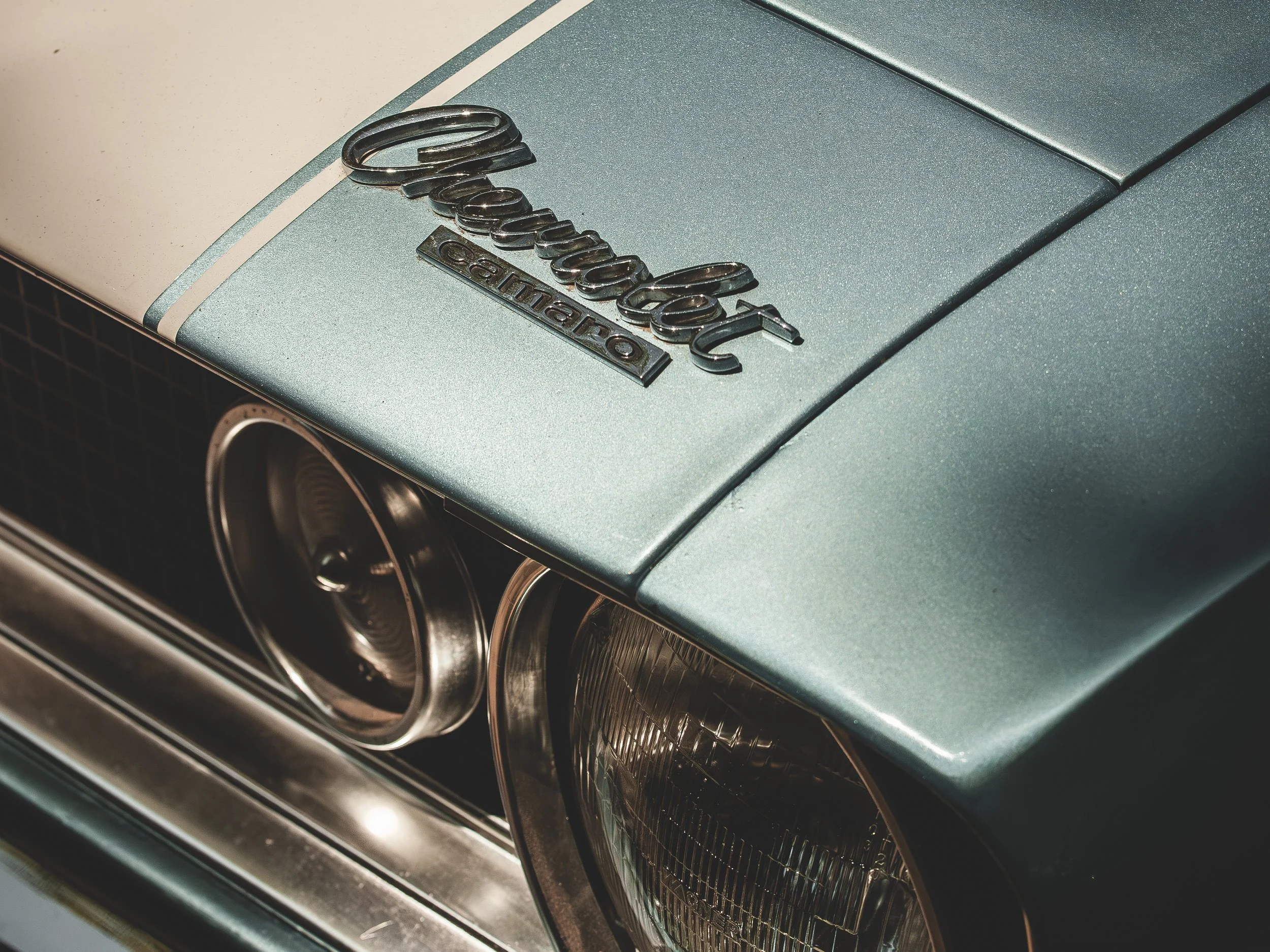 Primer plano del emblema y faros de un coche Chevrolet Camaro de color azul