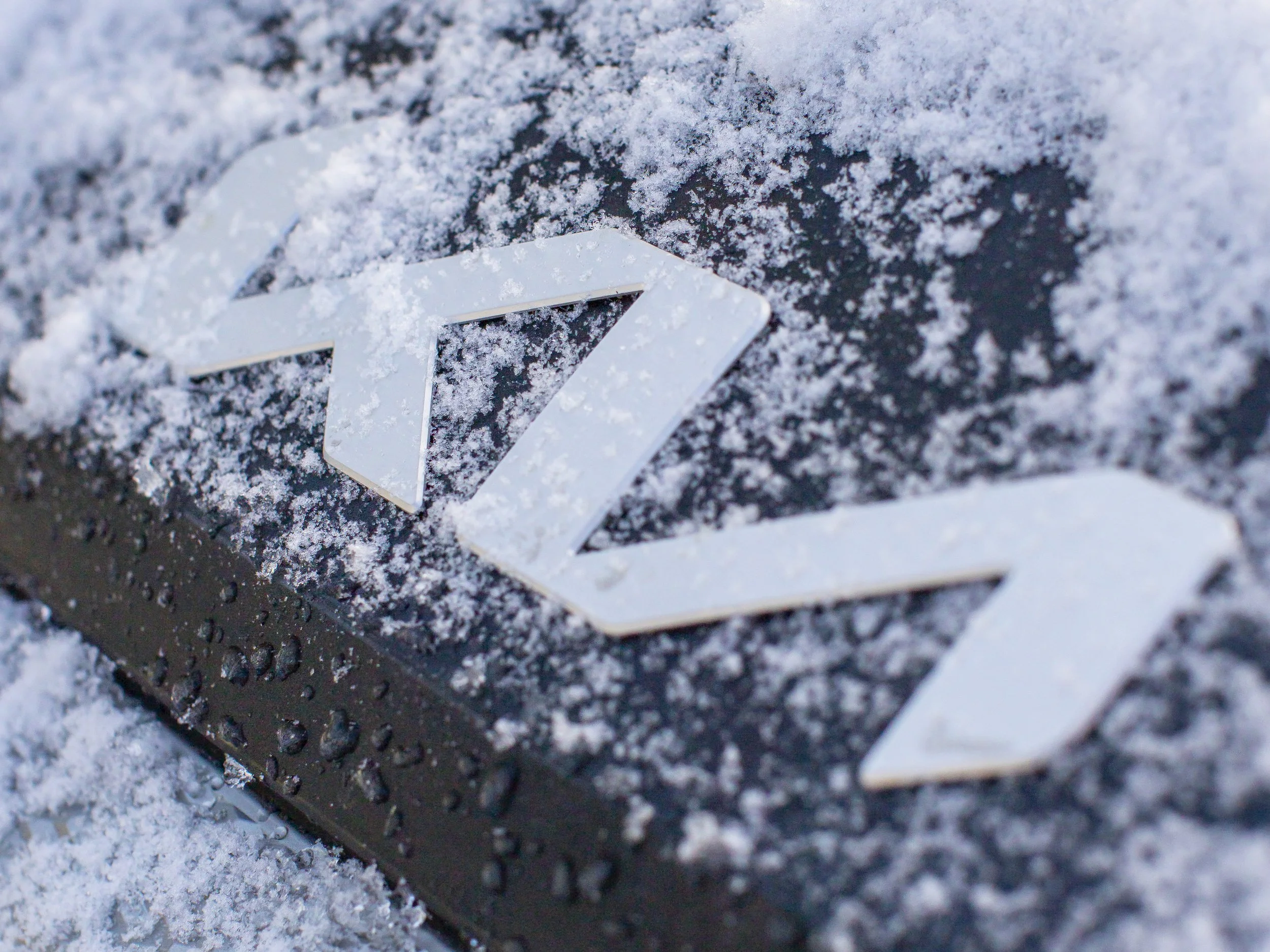 Logo de Tesla cubierto de escarcha en un fondo helado.