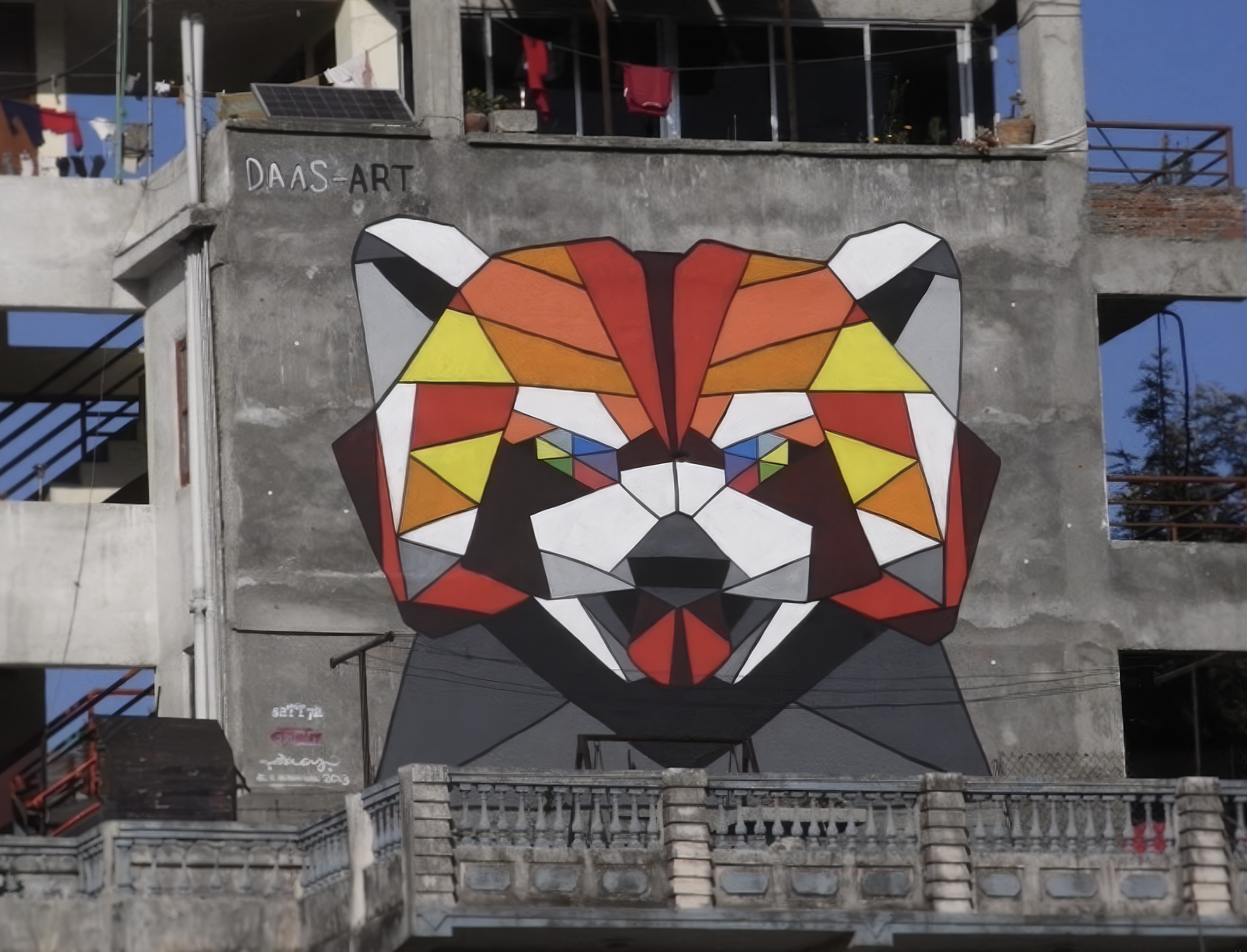 Work by the artist DAAS, Large geometric mural of a panda bear's face painted on a building's exterior wall.