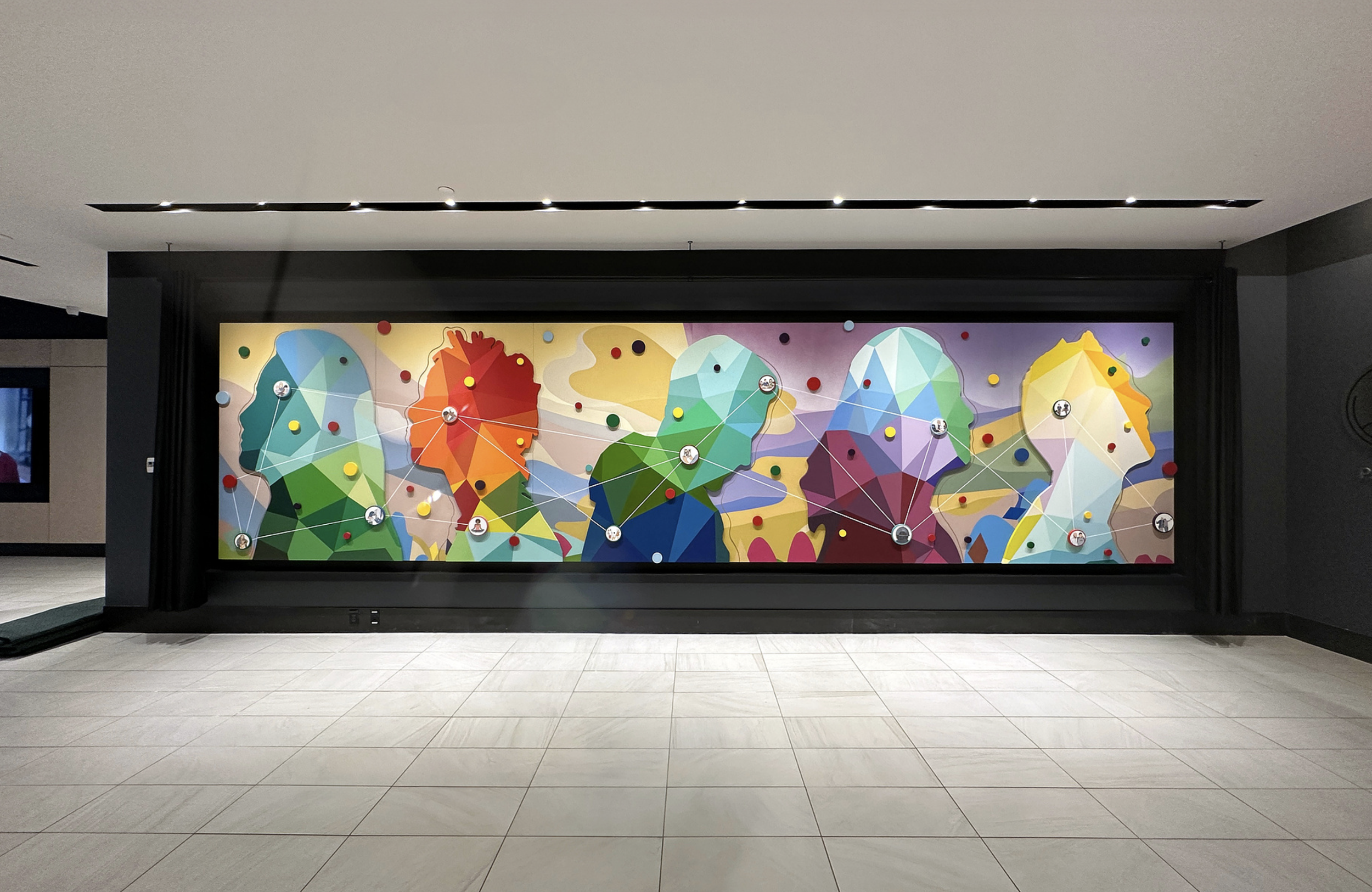 Work by the artist DAAS, Colorful abstract mural with polygonal faces of people, connected by lines and dots, on a wall in an indoor setting.