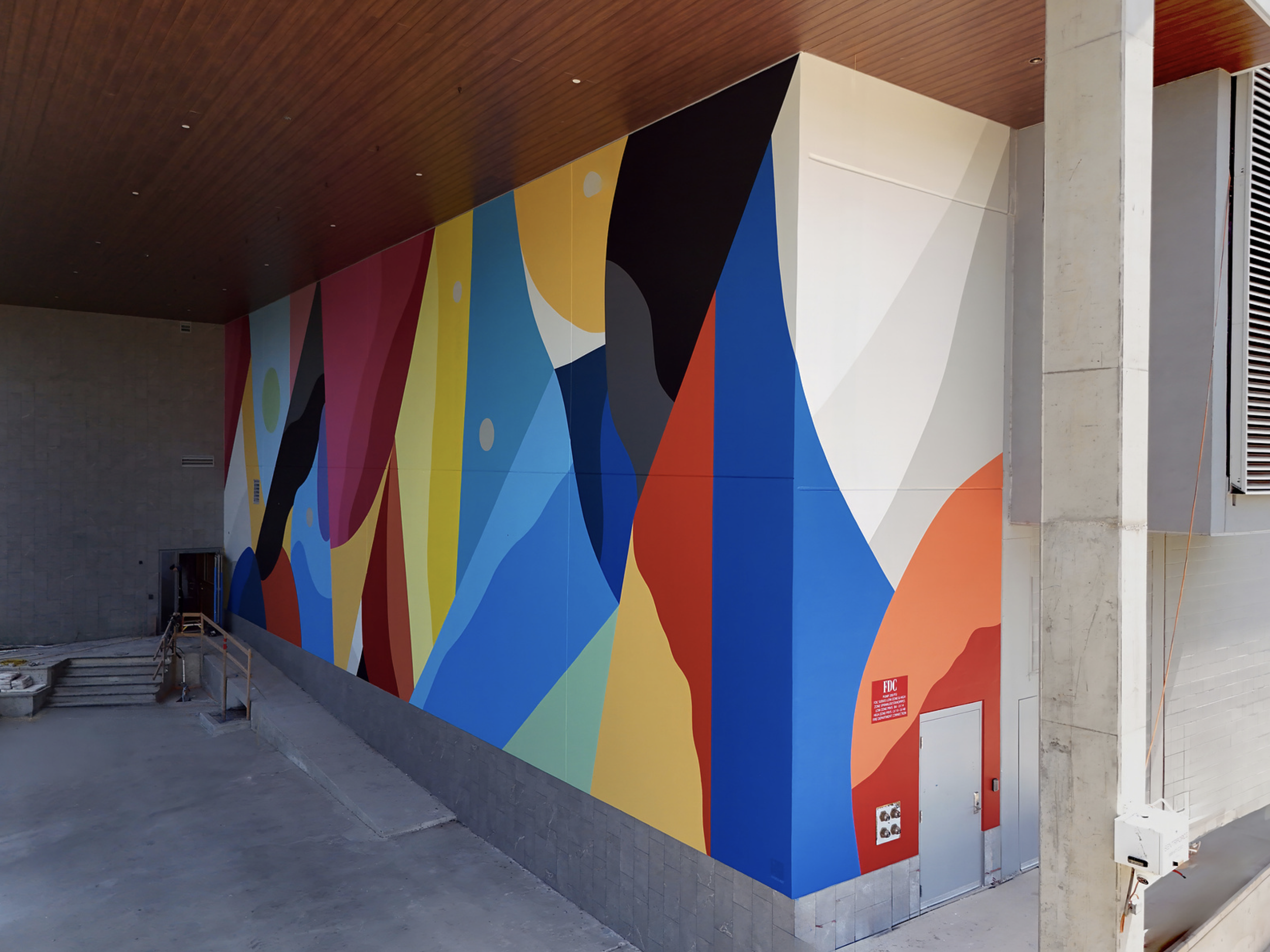 Work by the artist DAAS, Colorful abstract mural on a building exterior wall with geometric shapes and patterns.