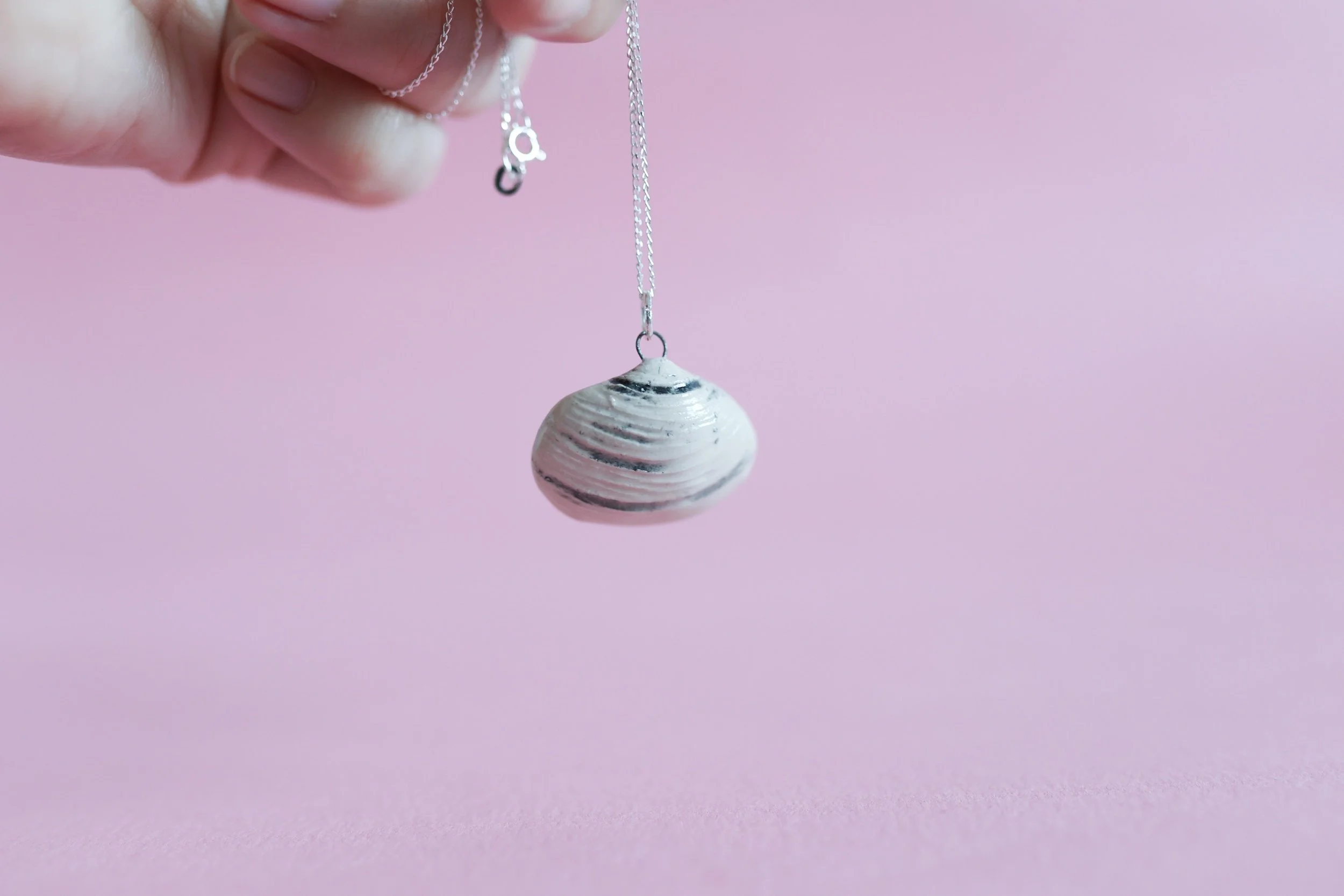 White a black clam shell pendant on sterling silver chain.