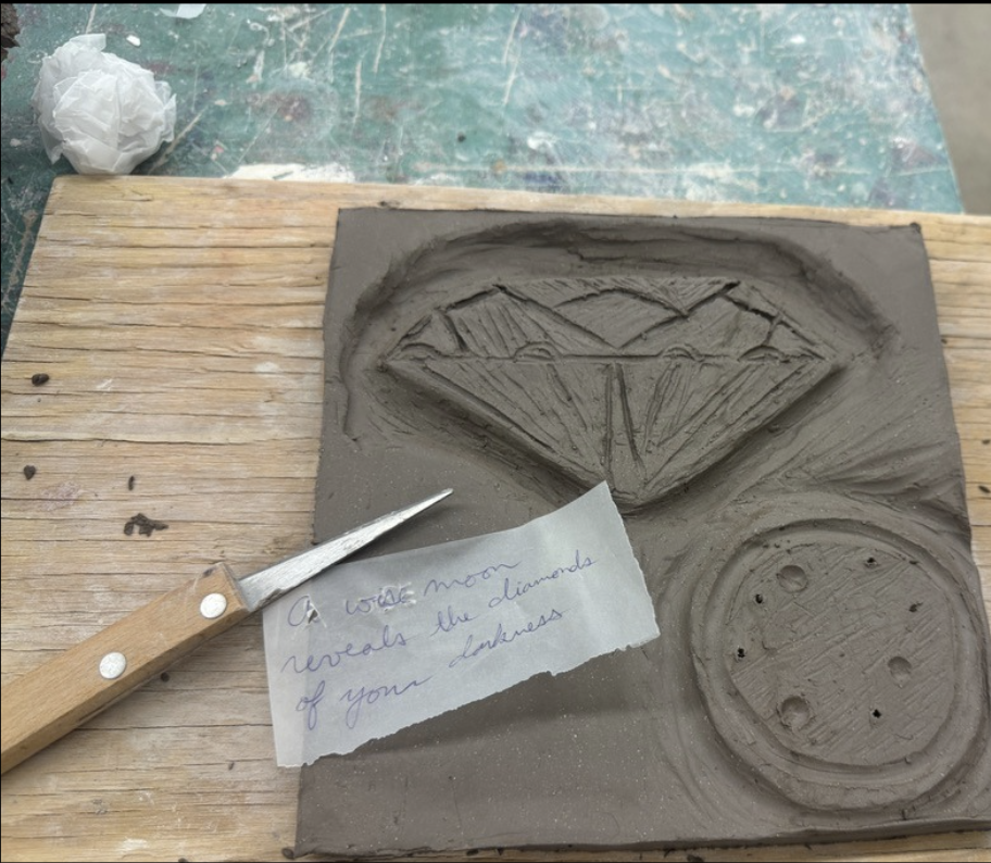 Engraved clay tile with note stating, "A wise moon reveals the diamonds of your darkness."