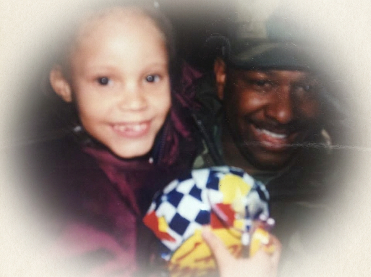 A young girl and an adult man smiling for a photo, with the girl holding a colorful toy.