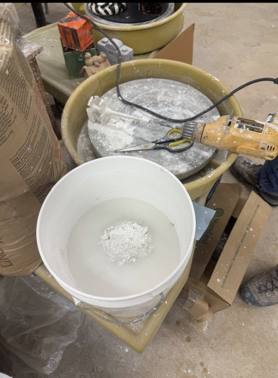 The beginning process of making the clay tiles. A bucket and a pottery wheel.