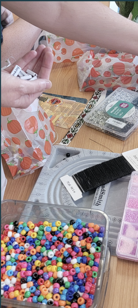Assortment of beads on a table with arm reaching over